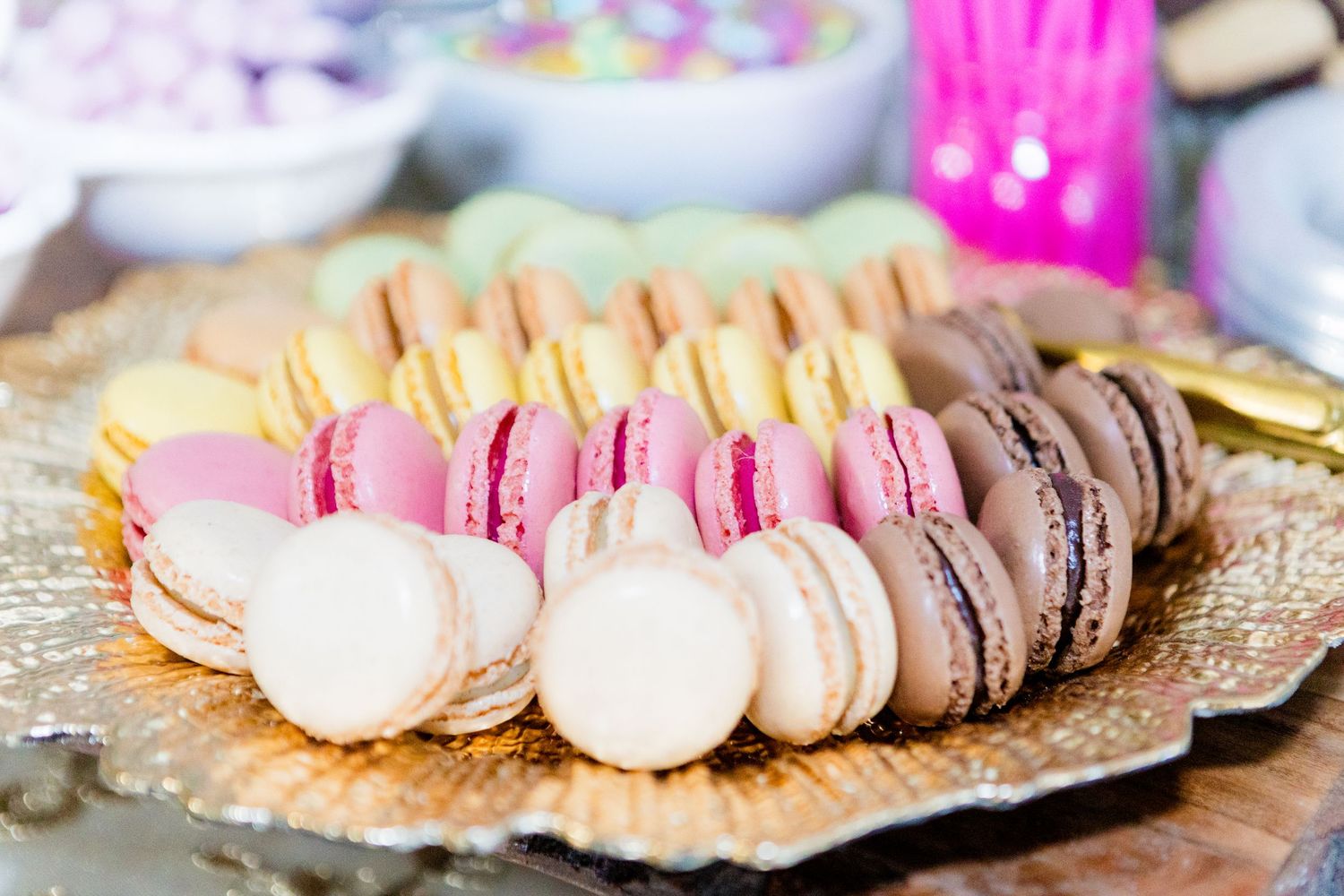 Colorful assorted French macarons displayed in a row, featuring pink, brown and cream colored varieties.