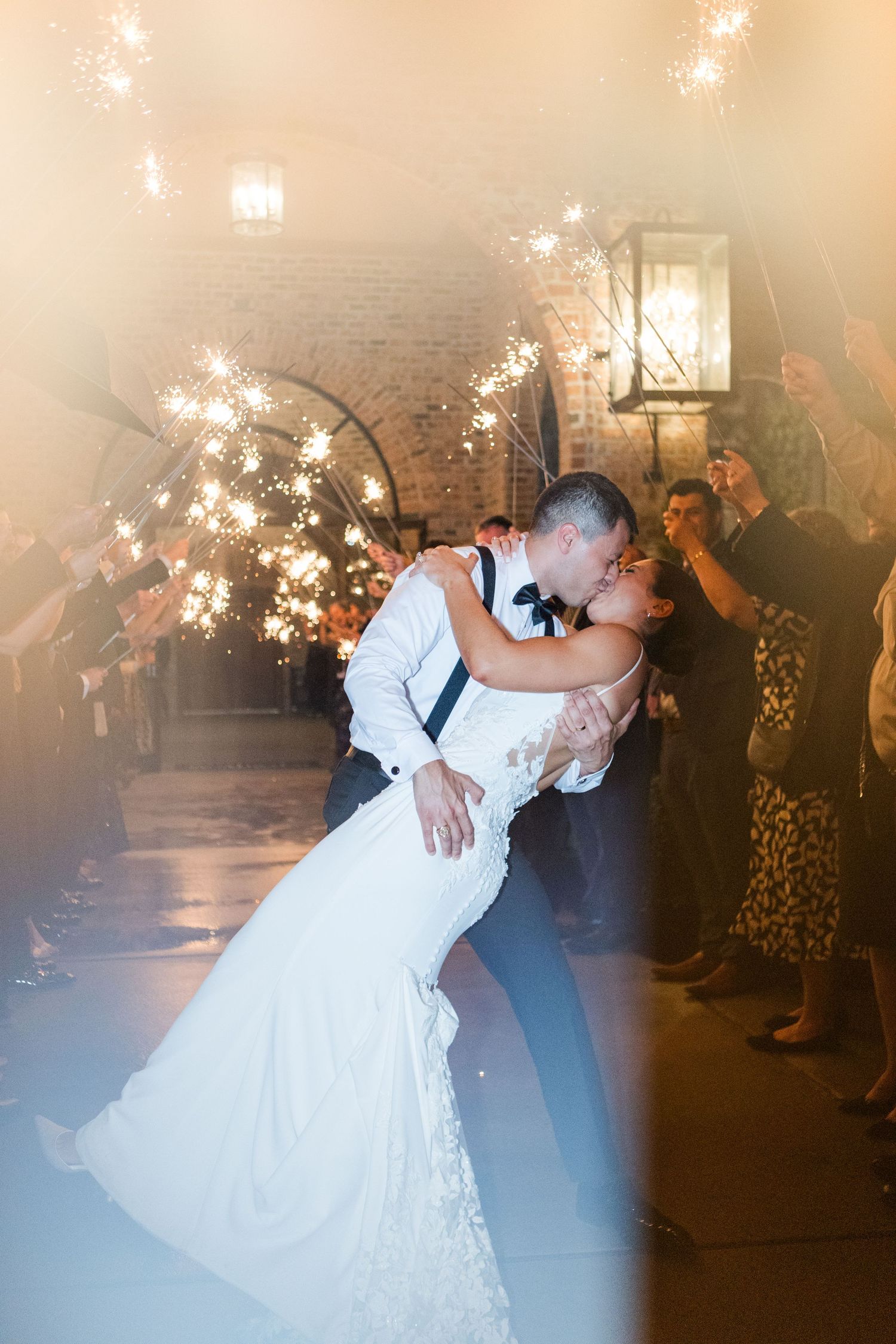 Romantic wedding sparkler exit with couple sharing a dip kiss surrounded by lit sparklers.