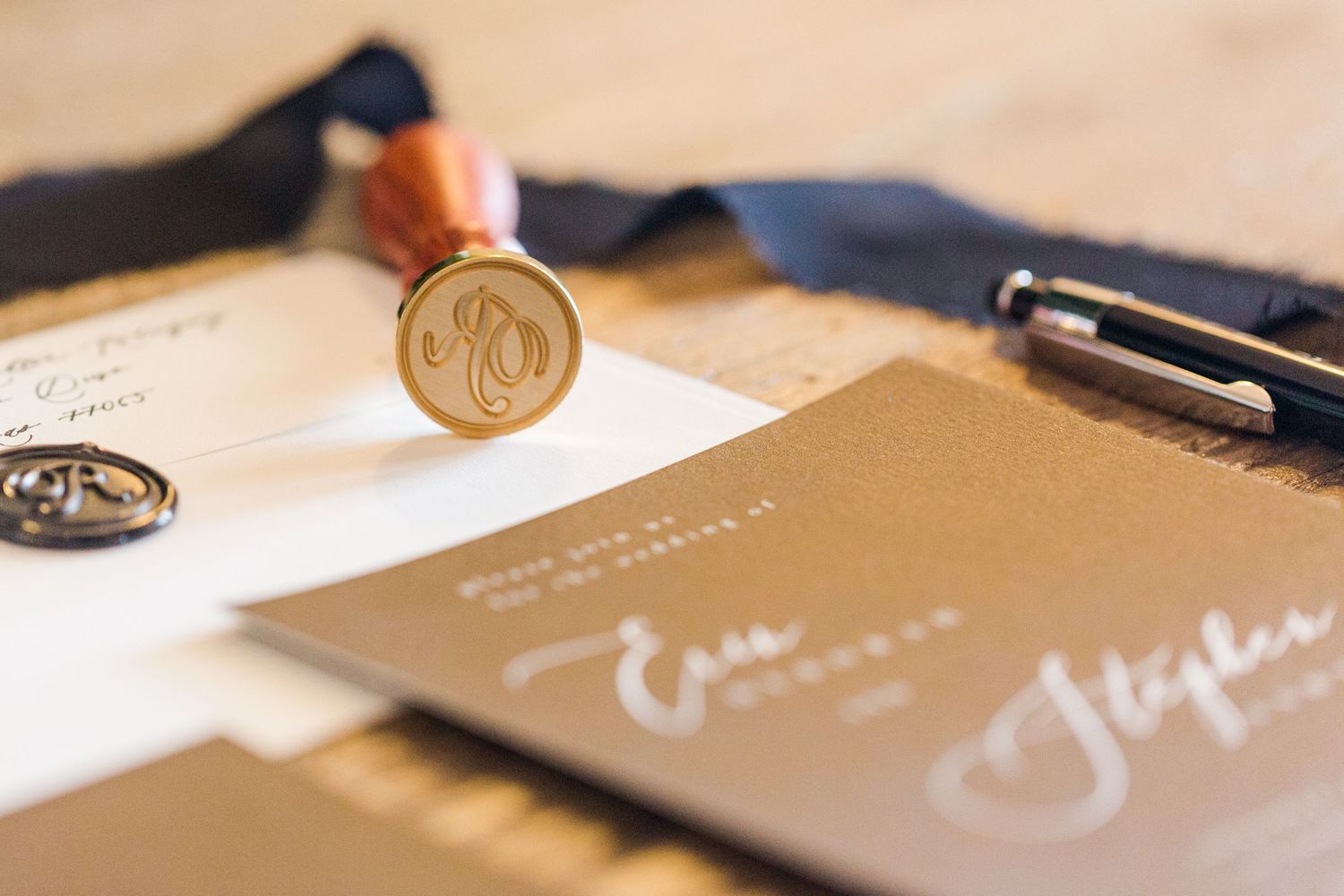 Close-up of wedding invitation suite with gold wax seals and calligraphy details.