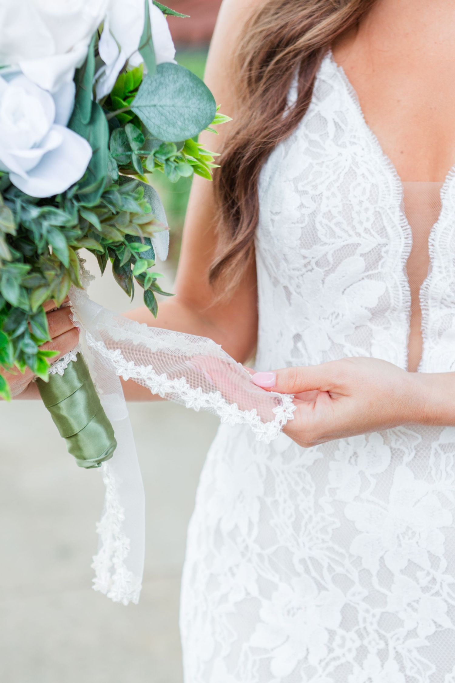 Close-up details of intricate lace wedding dress and floral bouquet.