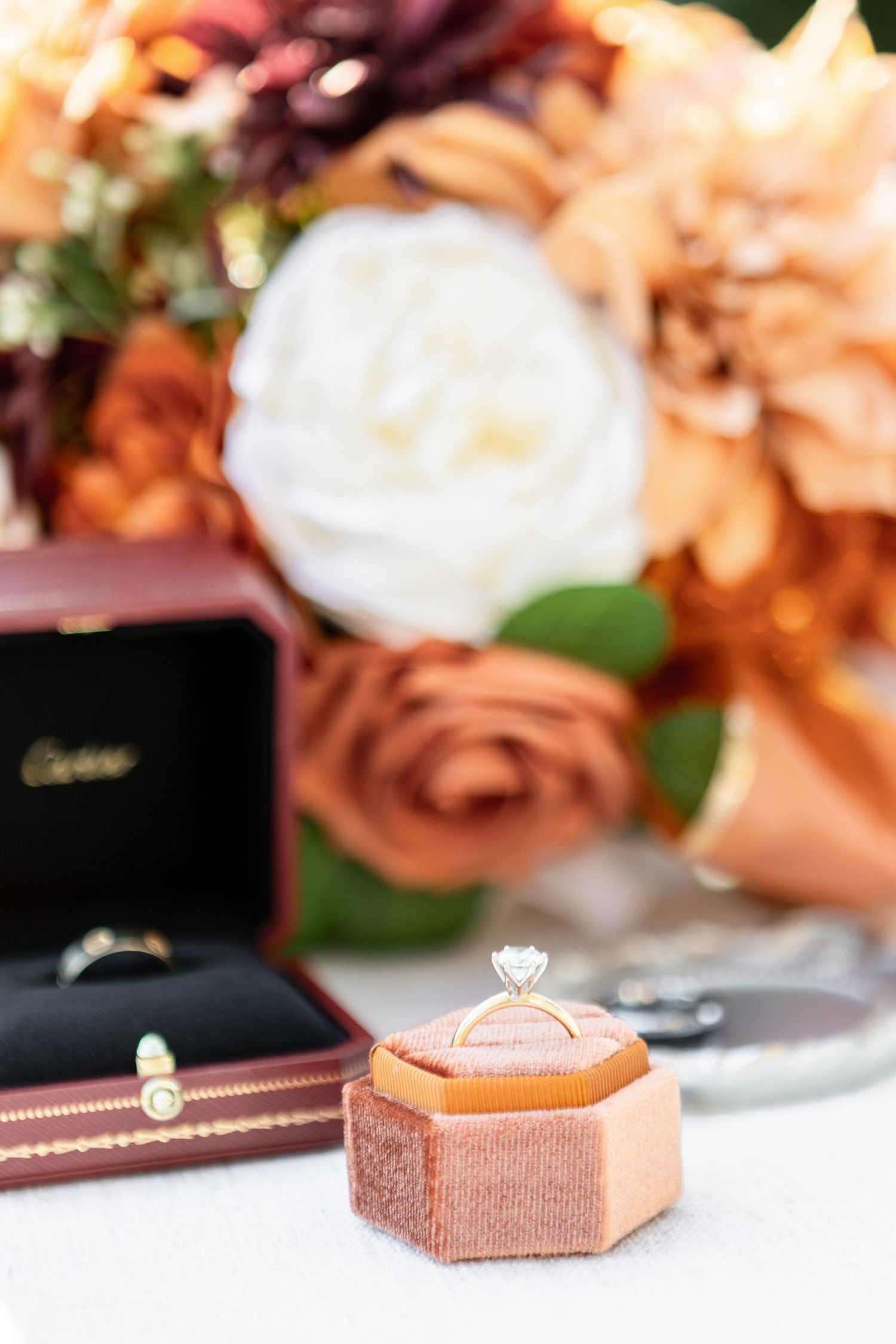 Elegant engagement rings displayed on peach-colored velvet ring holders.