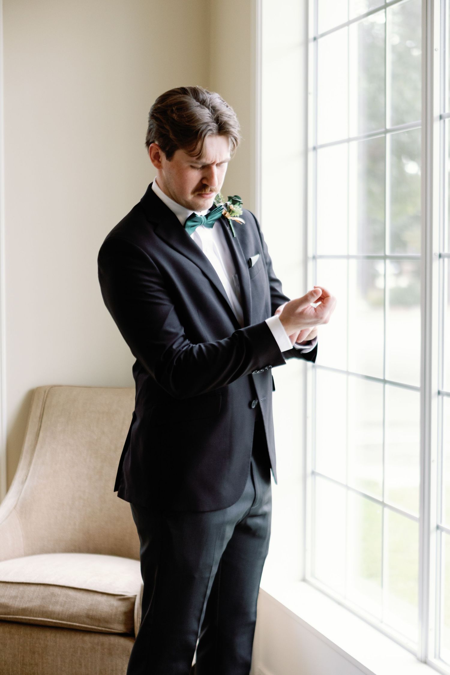 Four sequential photos show someone in a black suit checking their phone while standing near bright windows.