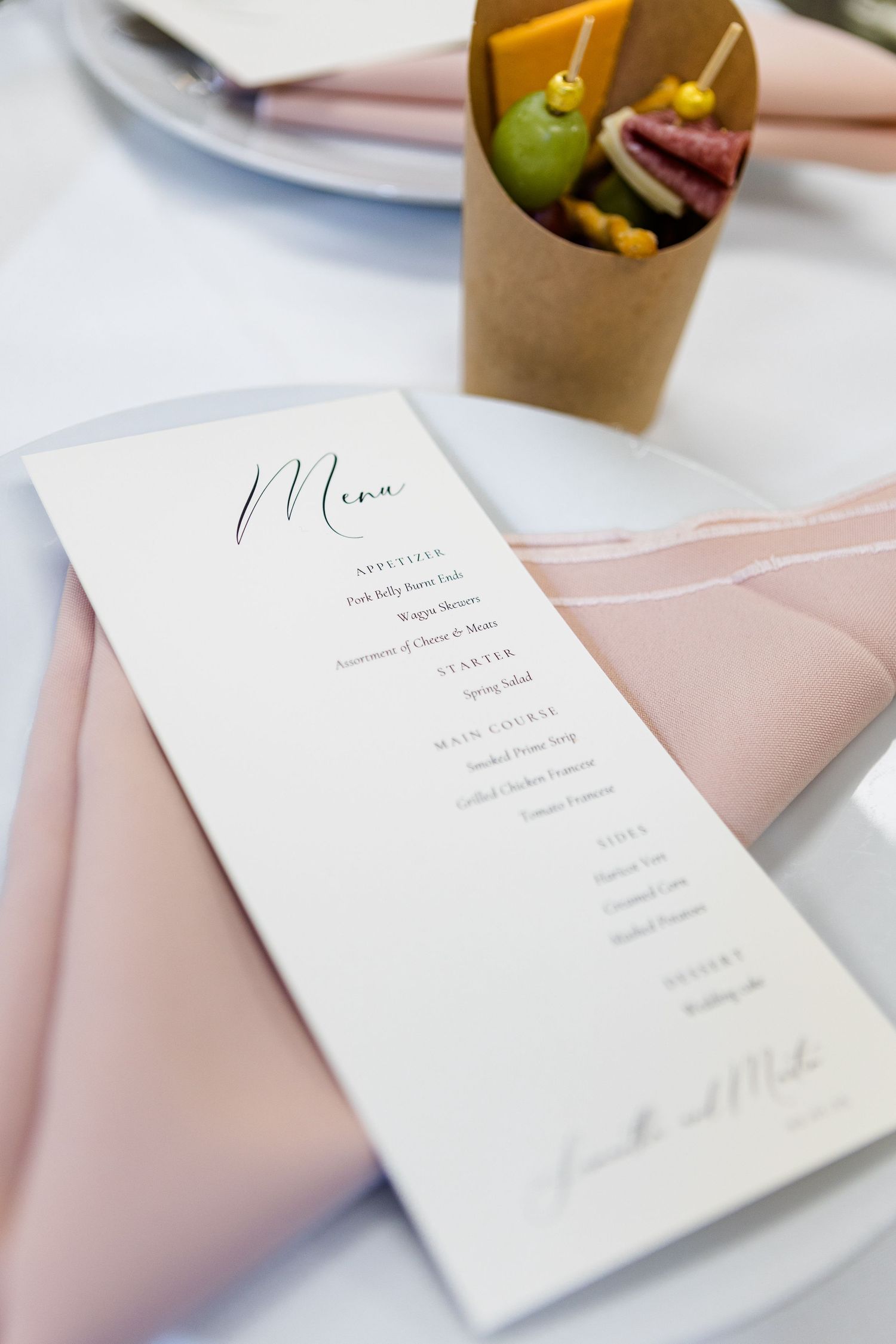 Minimalist wedding menu cards displayed on light pink linens.