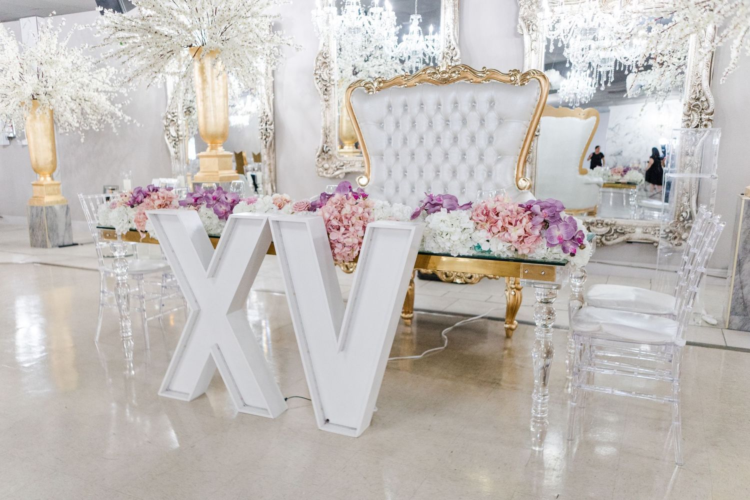 Large white decorative Roman numerals XV displayed in an elegant white and gold venue.