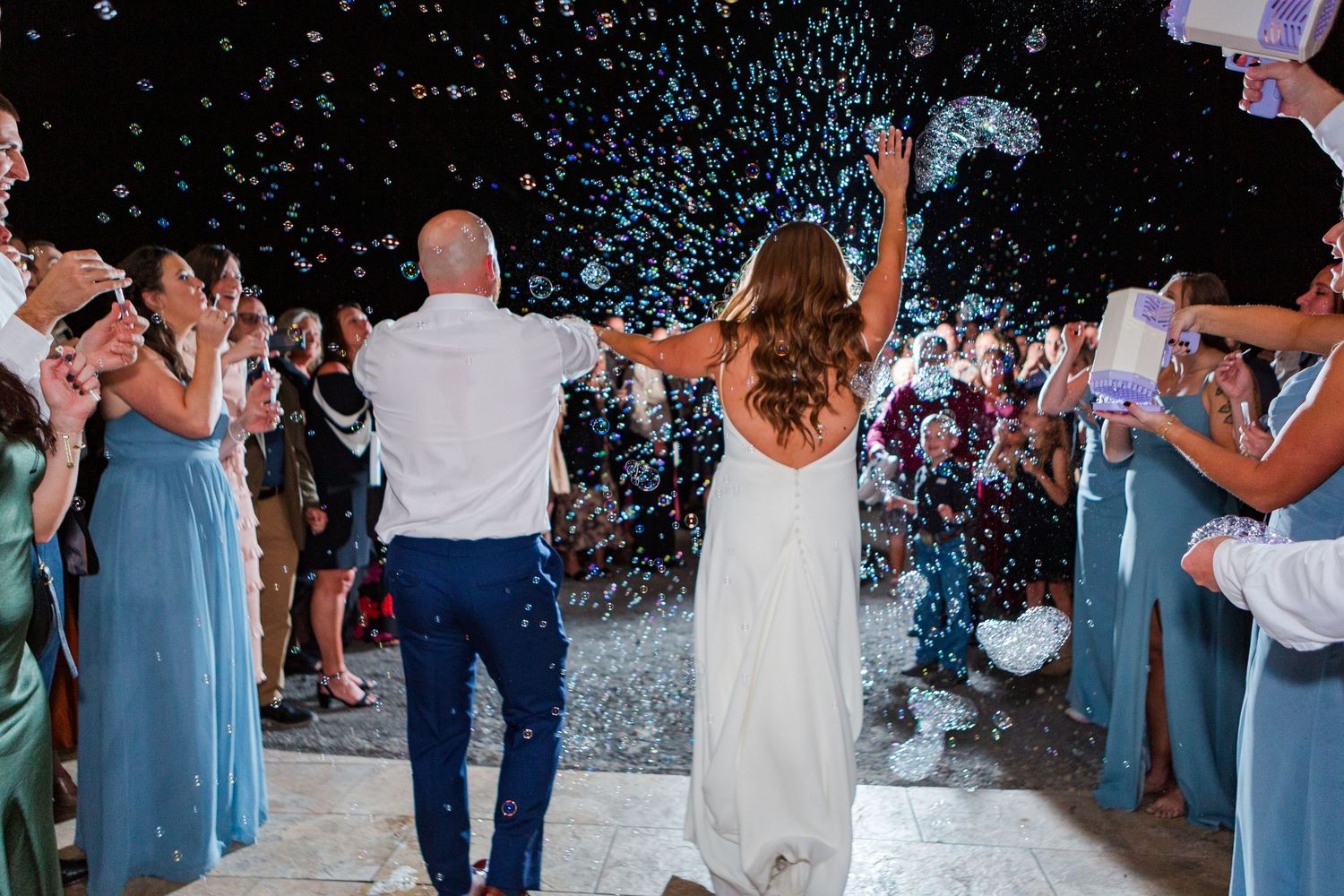White confetti falling over celebratory guests at a wedding reception.