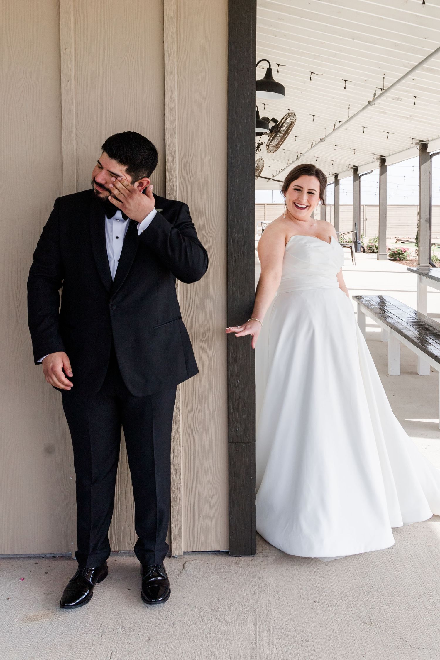 Wedding couple creates fun poses while separated by pillars for their first look photos.