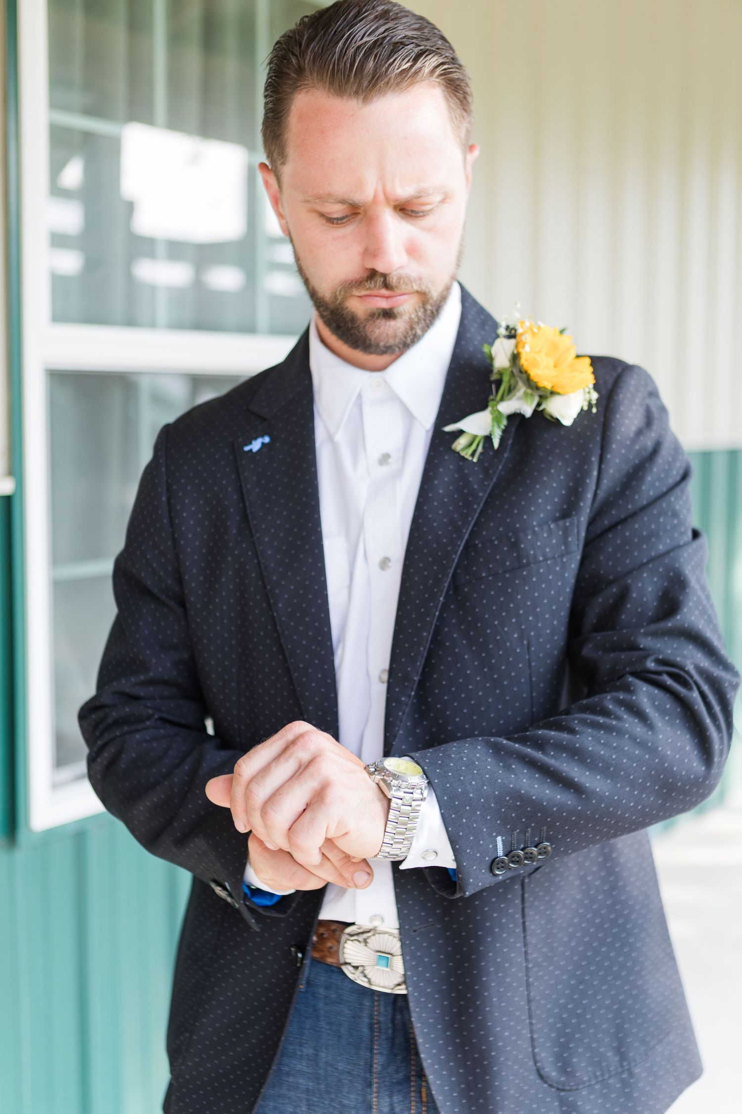 Groom in navy suit checking time on watch before ceremony.