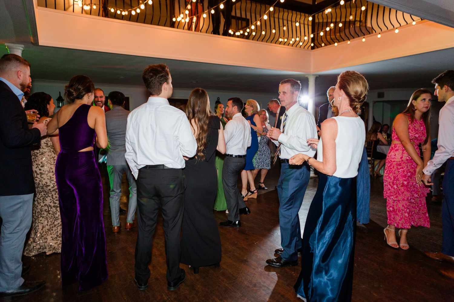 Wedding reception crowd dancing under dimmed lights in elegant venue.