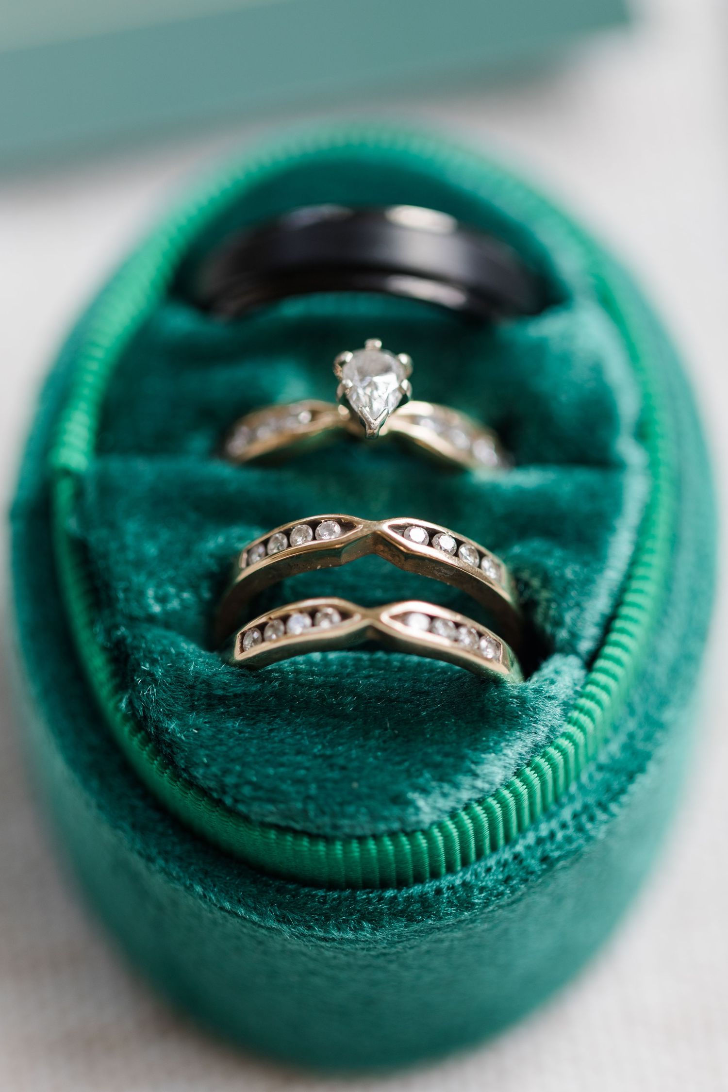 Diamond engagement ring and wedding band nestled in a green velvet ring box shown from multiple angles.