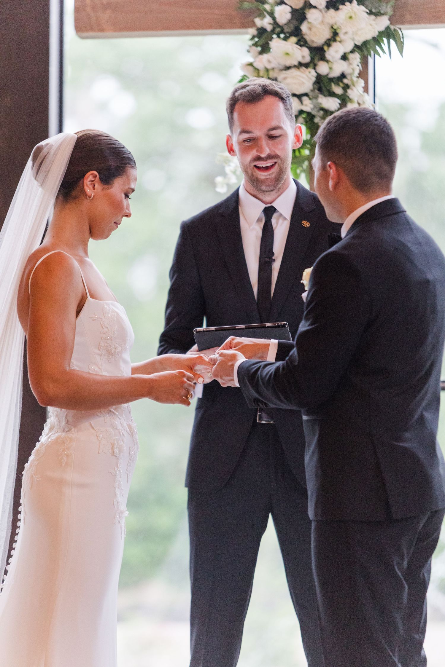 A sequence of wedding ceremony moments captured in front of large windows and floral arrangements.