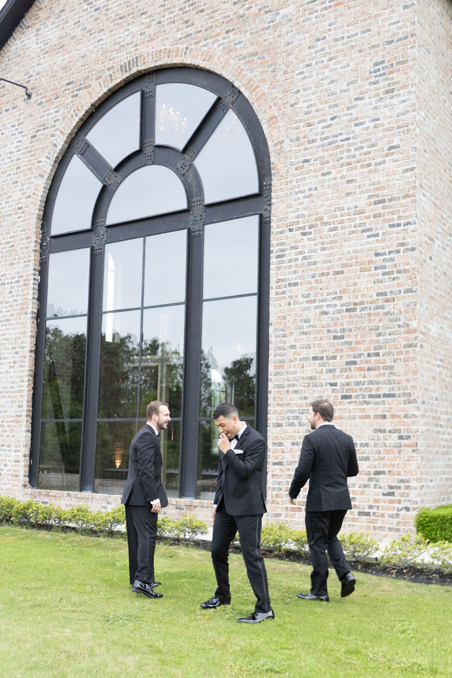 Wedding party members in formal attire engaging in candid moments outside venue.