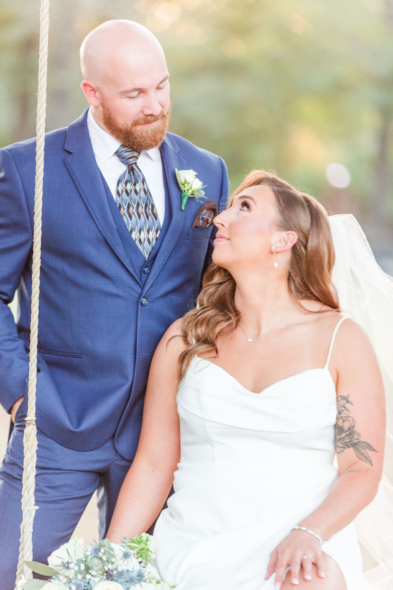 Romantic swing photos of the wedding couple in elegant navy and white attire.