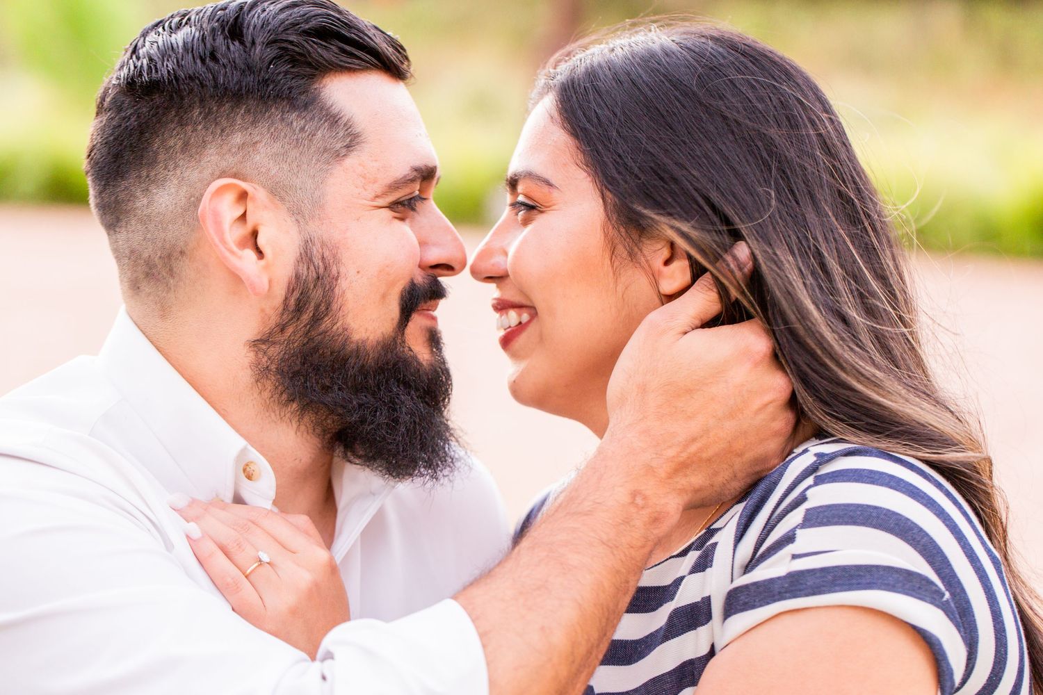 Couple in casual attire sharing intimate moment outdoors during sunset photography session.