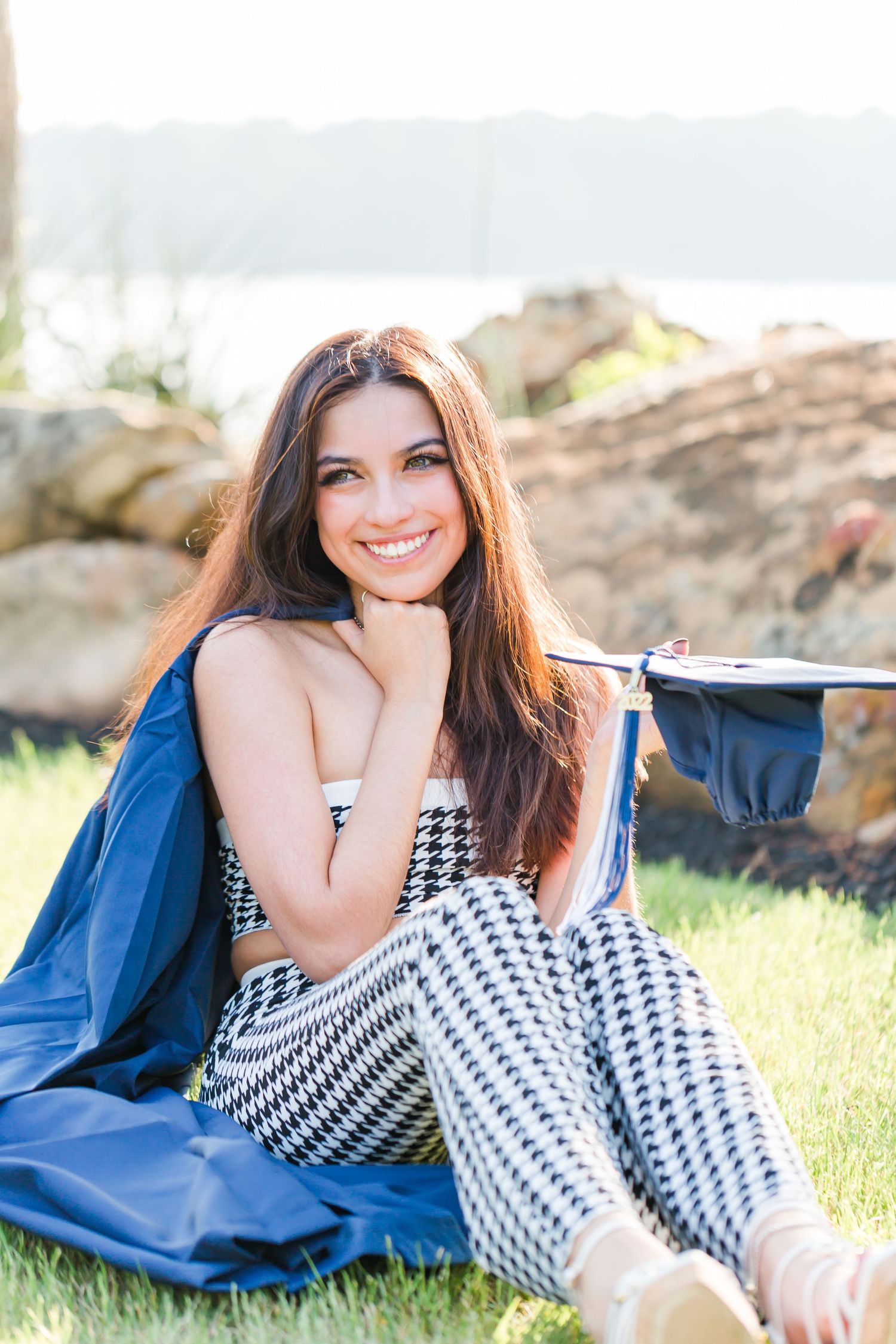 girl sitting on grass holding cap