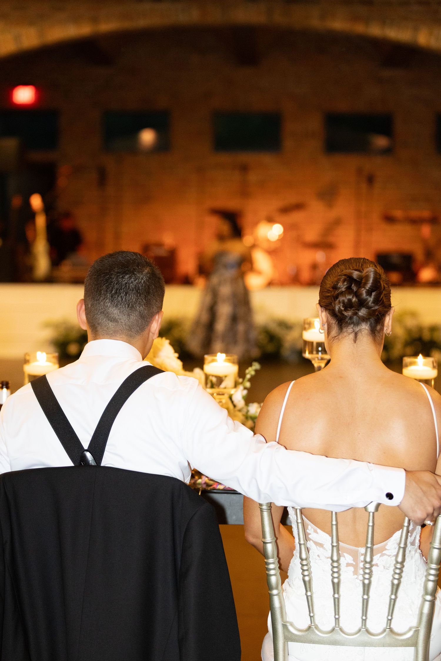 Wedding reception guests in formal attire seated at elegant tables with floral centerpieces.