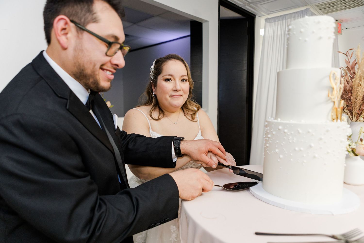 Wedding cake cutting ceremony with classic white tiered cake at an elegant reception.