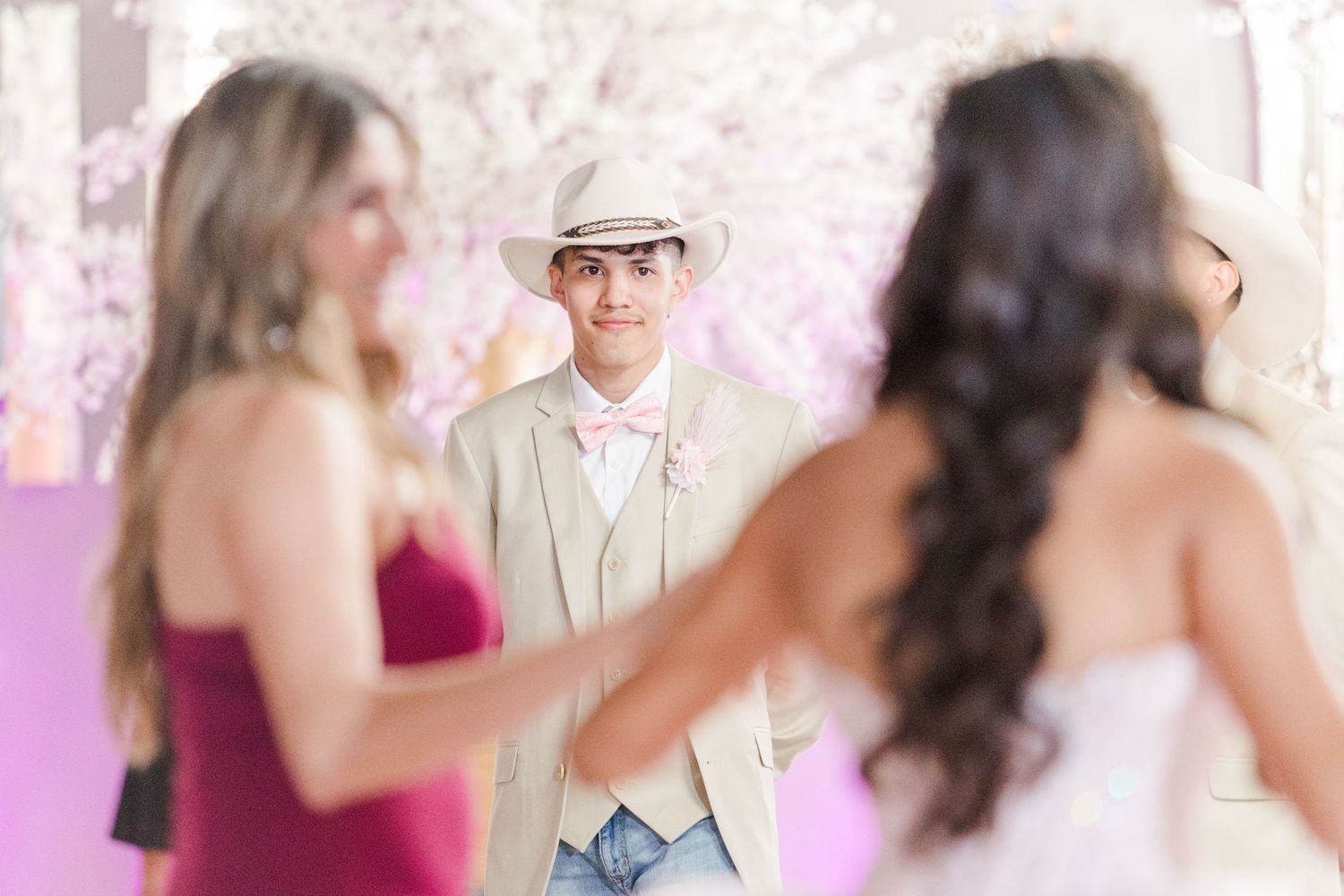 Party guests in formal attire enjoying a celebration in an elegant white venue.
