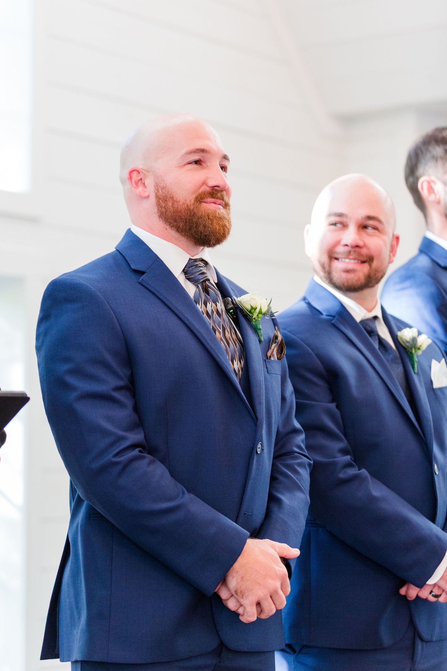 Groomsmen in navy suits with boutonnières standing at wedding altar.
