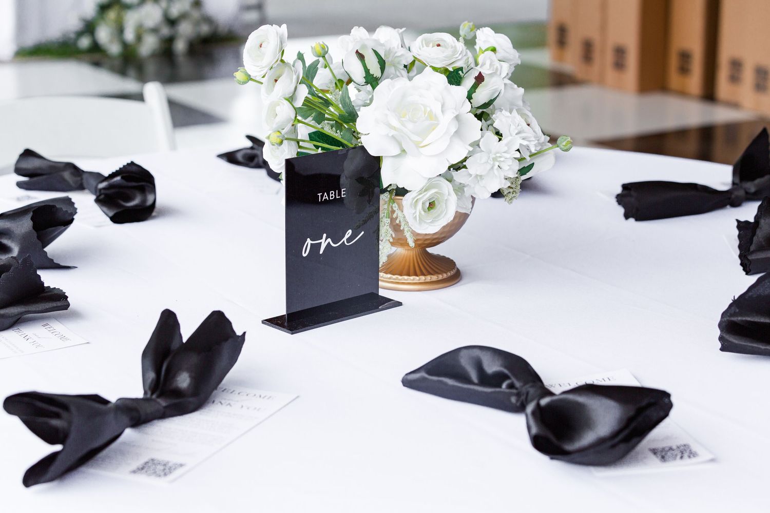 Black bow ties and wedding accessories arranged on white table surface.