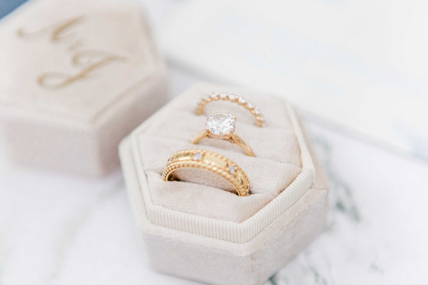 Delicate ring displayed in white jewelry box with soft lighting.