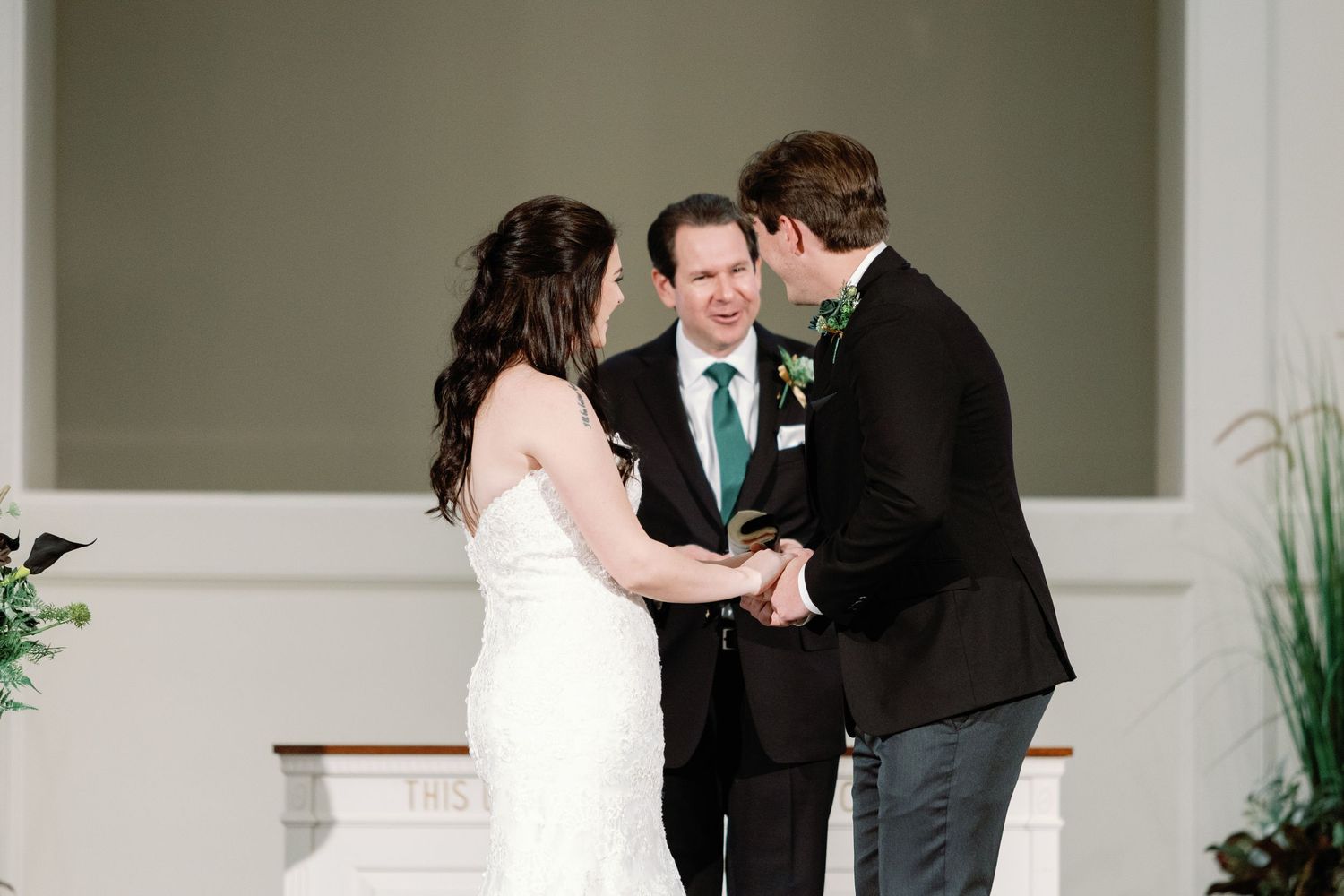 Bride and groom share an intimate moment during their wedding ceremony in an elegant white-walled venue.