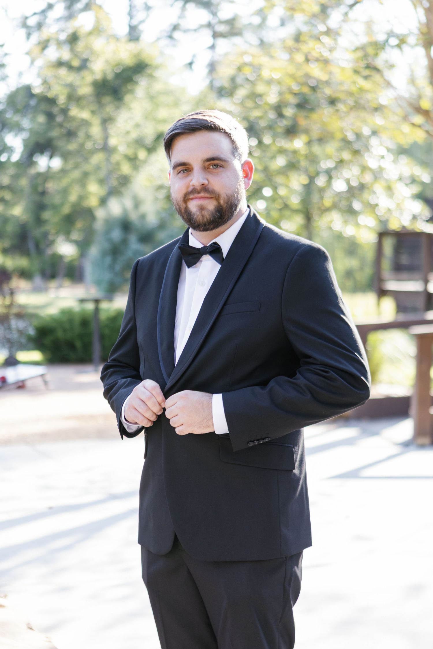 Groom in classic black tuxedo adjusts his bowtie before the ceremony.