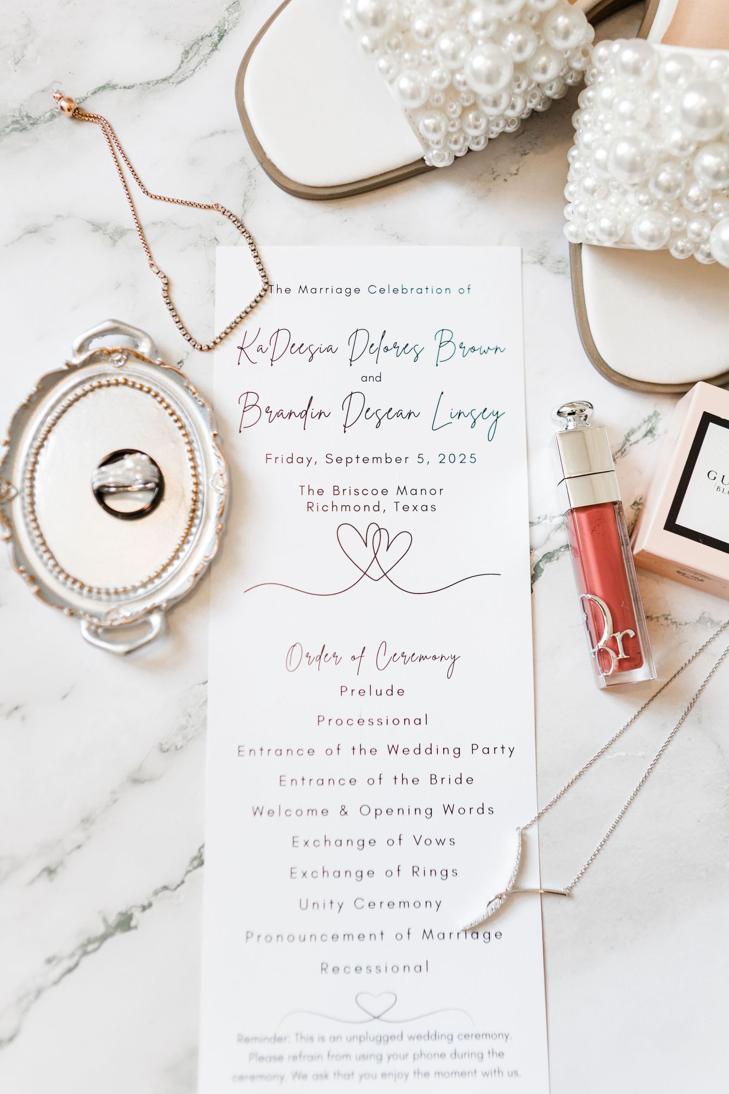 Elegant wedding details featuring pearl jewelry, pink lipstick, and white floral invitations on marble background.