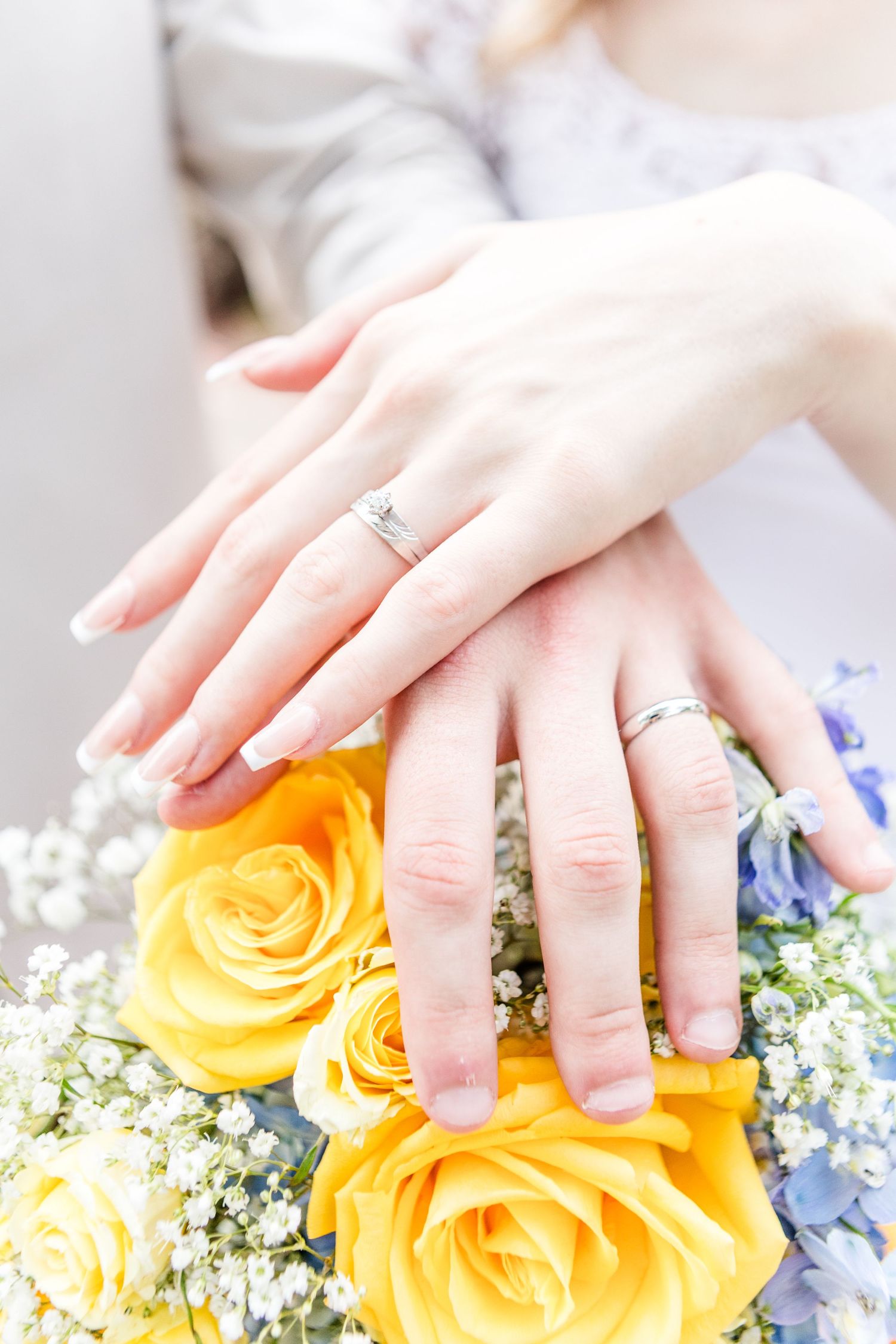 Close-up shots of hands with wedding rings against a bouquet of yellow roses and baby's breath.