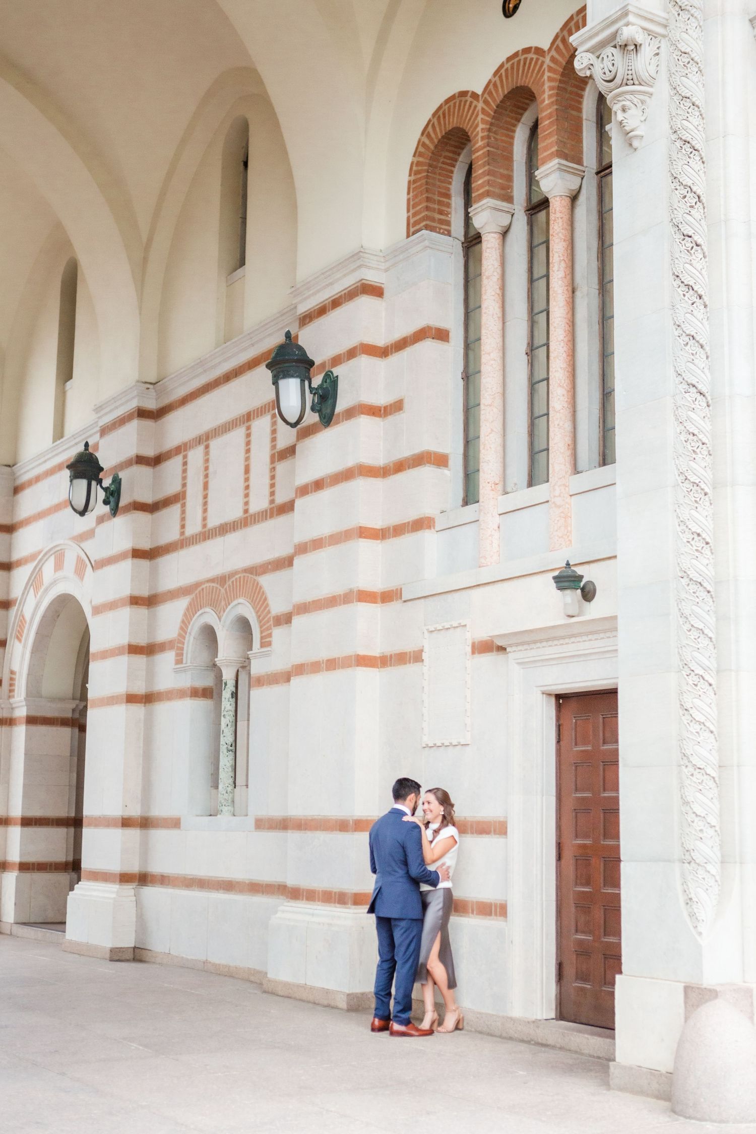 Elegant architectural backdrop frames romantic couple beneath arched colonnade.