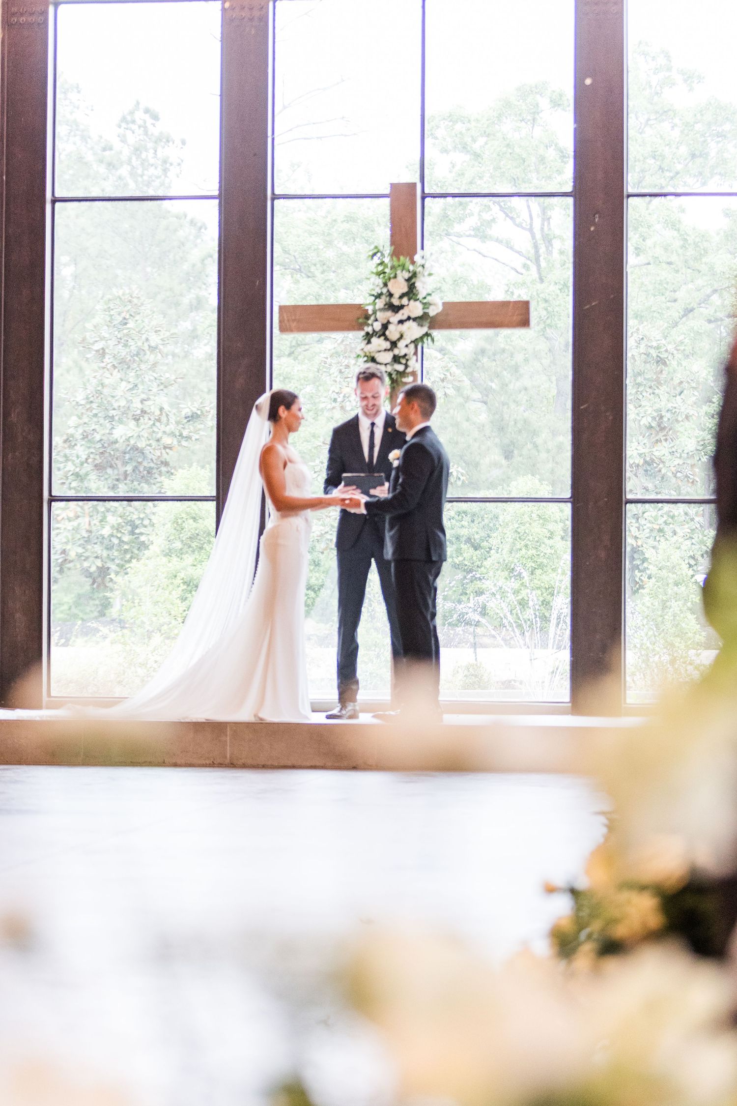 Wide angle view of wedding ceremony with natural light streaming through architectural windows.