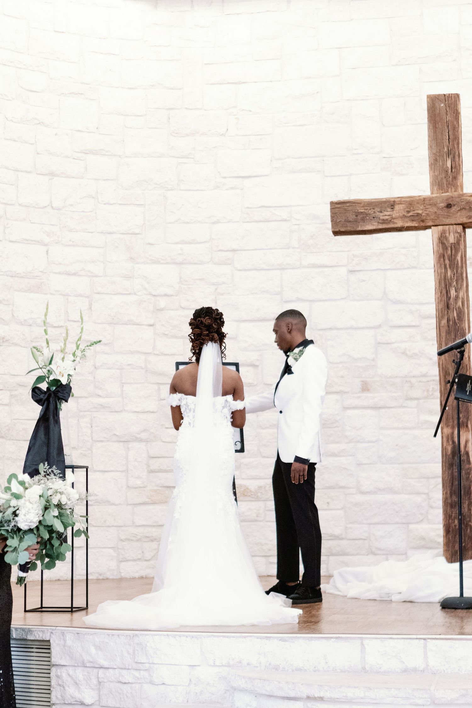 A white chapel interior decorated with lanterns and greenery for a wedding ceremony.