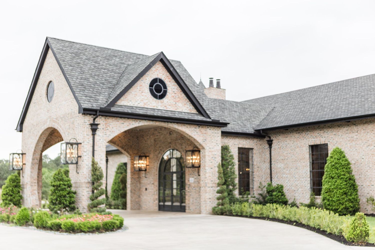 Stone facade of an elegant wedding venue with arched entrance and manicured landscaping.