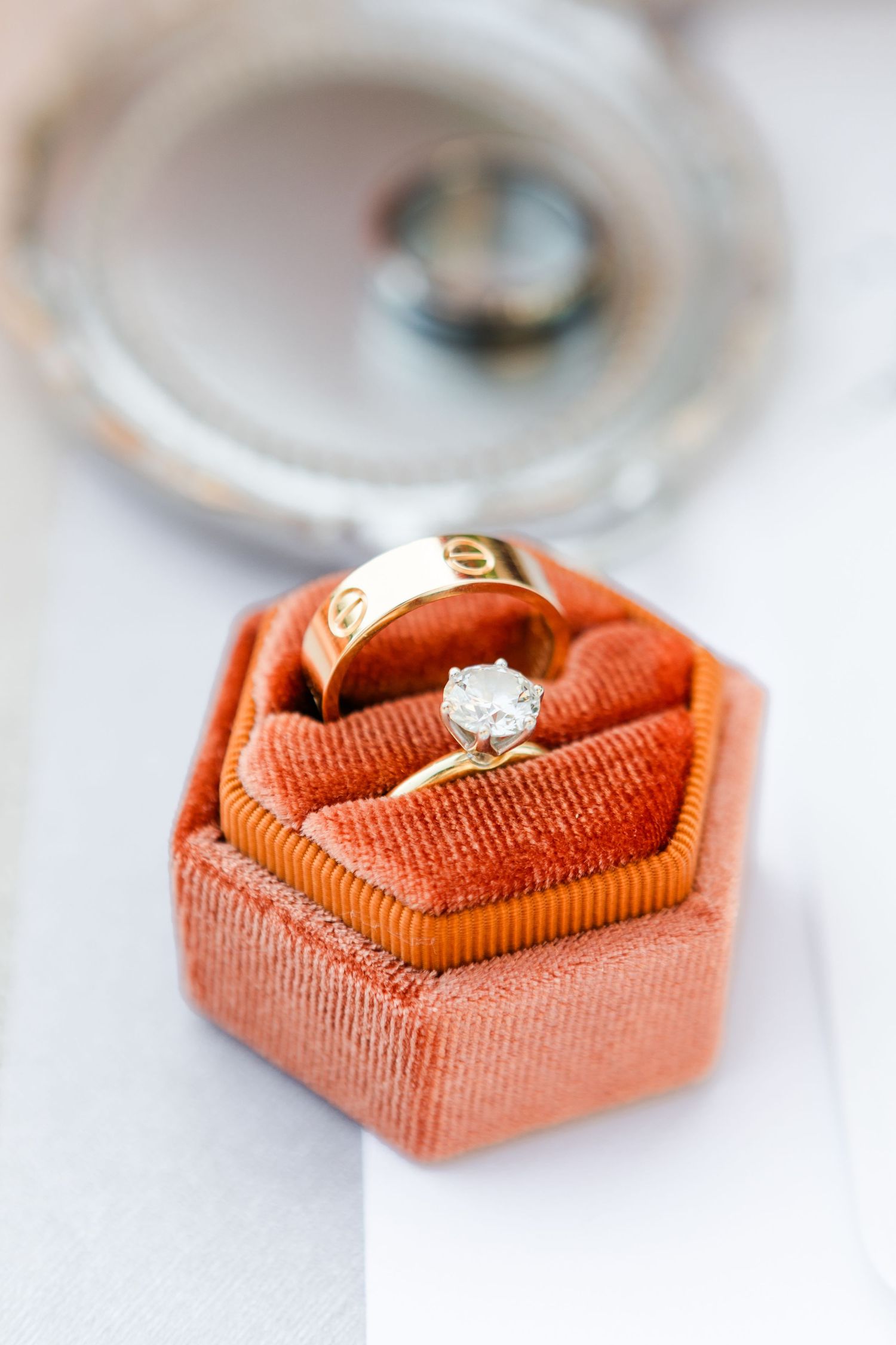Wedding rings nestled in coral-colored velvet ring boxes arranged in a sequence.