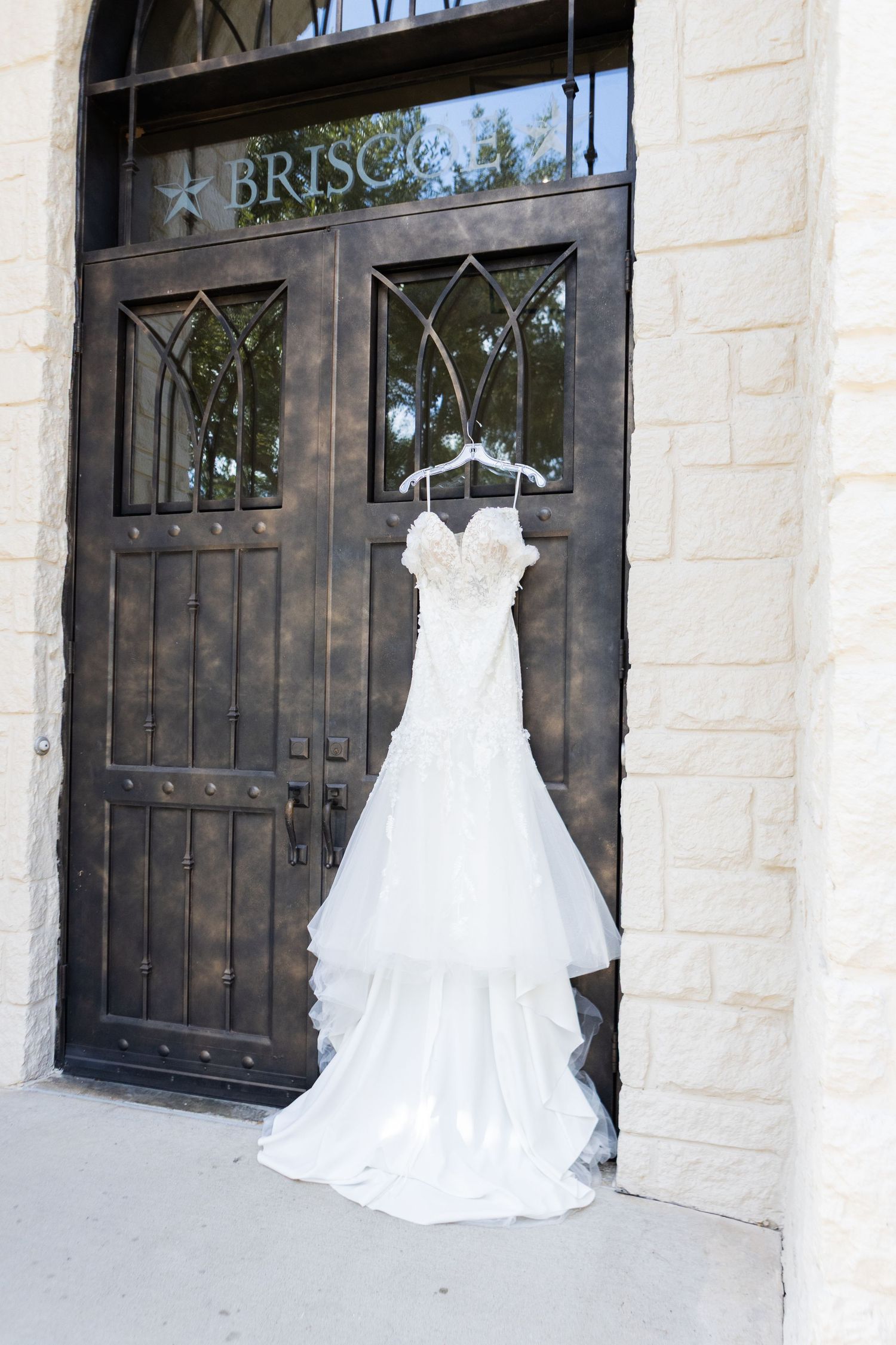 Display of elegant white wedding dresses arranged against stone building walls.
