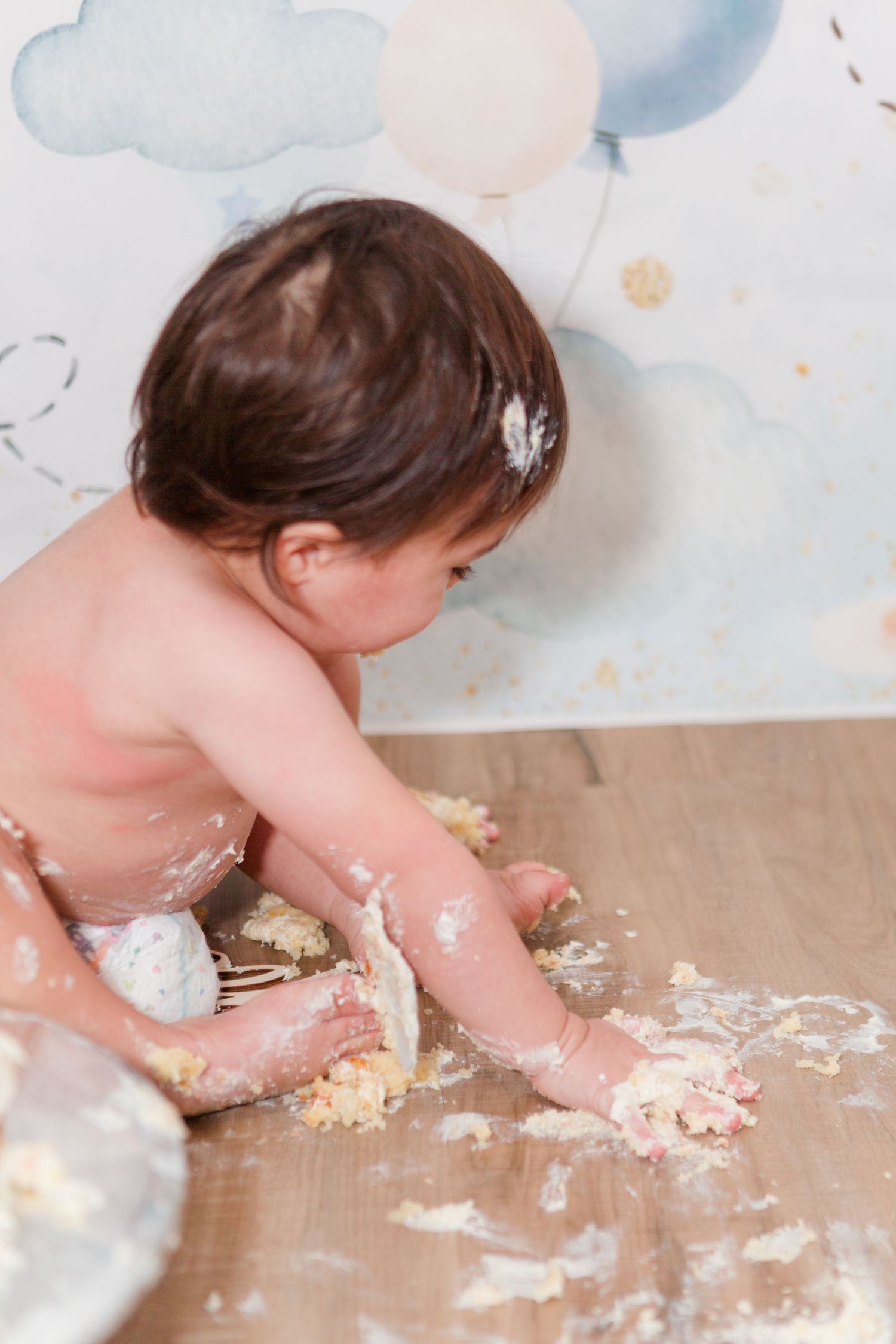 Small child playing with smashed cake during a cake smash photo session.