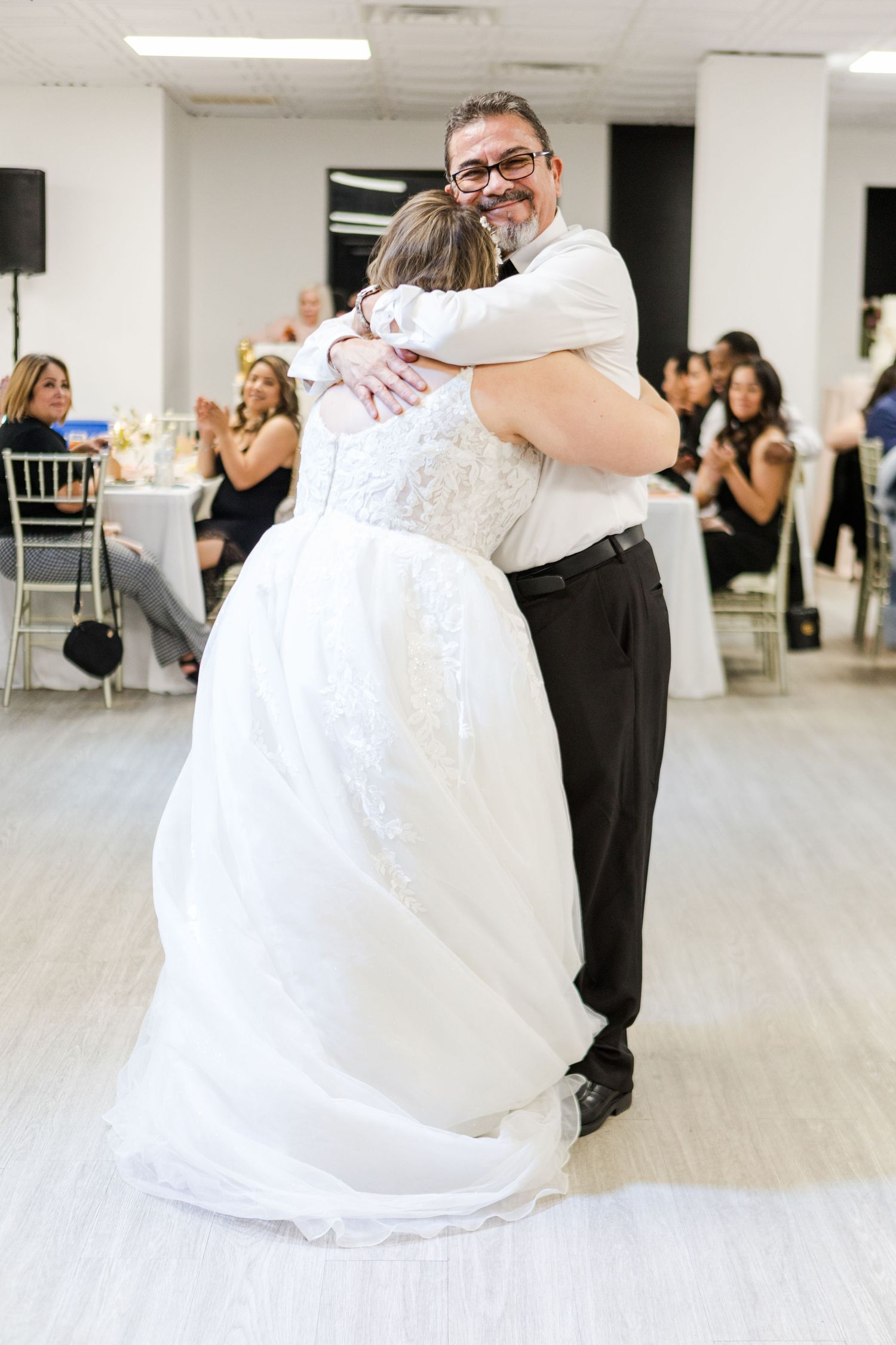 A romantic dance between a couple during their wedding reception in a bright white ballroom.