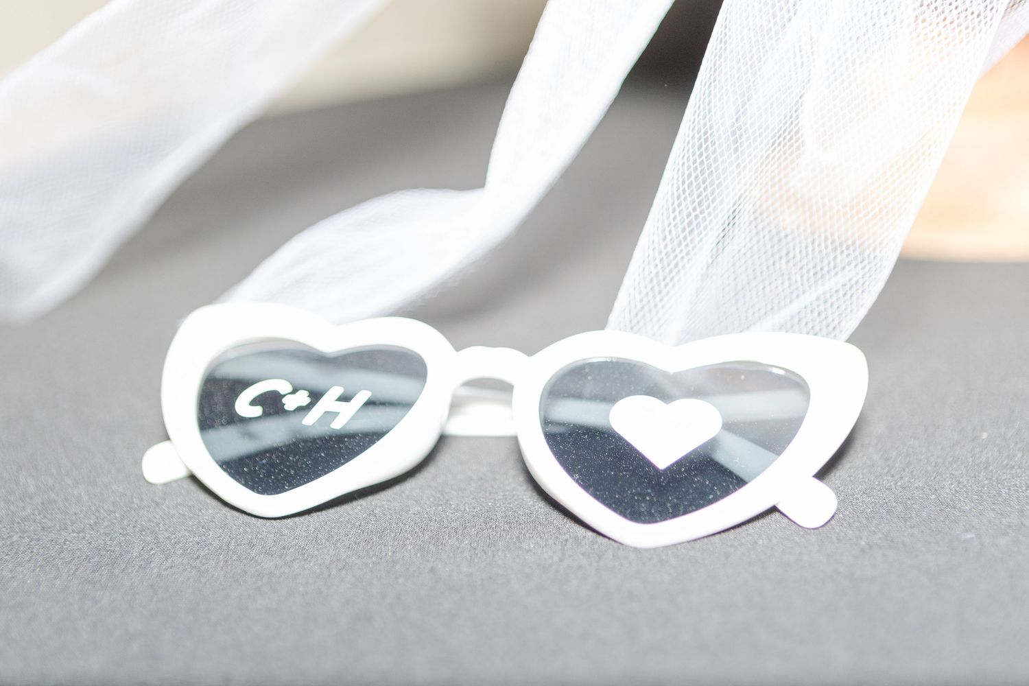 White heart-shaped wedding sunglasses displayed on a light surface.