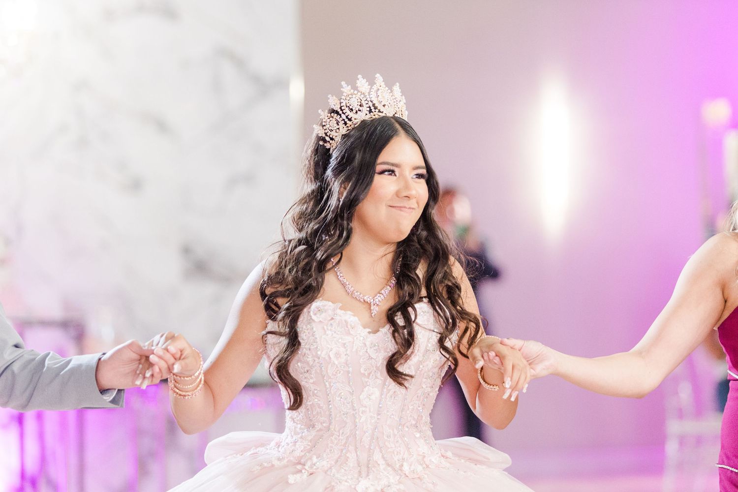 Celebration event in an elegantly decorated room with purple lighting and chandeliers.