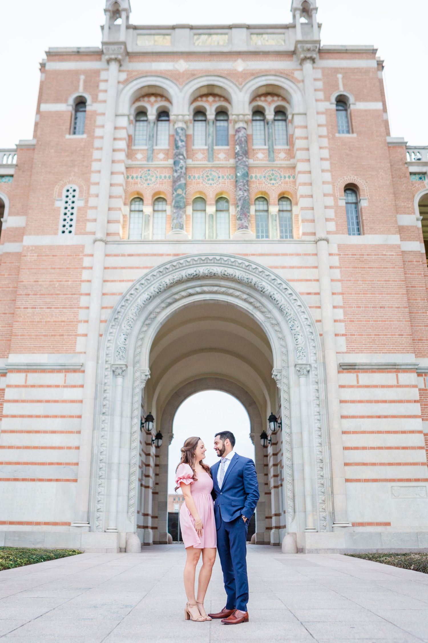 A romantic moment unfolds in front of an elegant Mediterranean-style building facade.