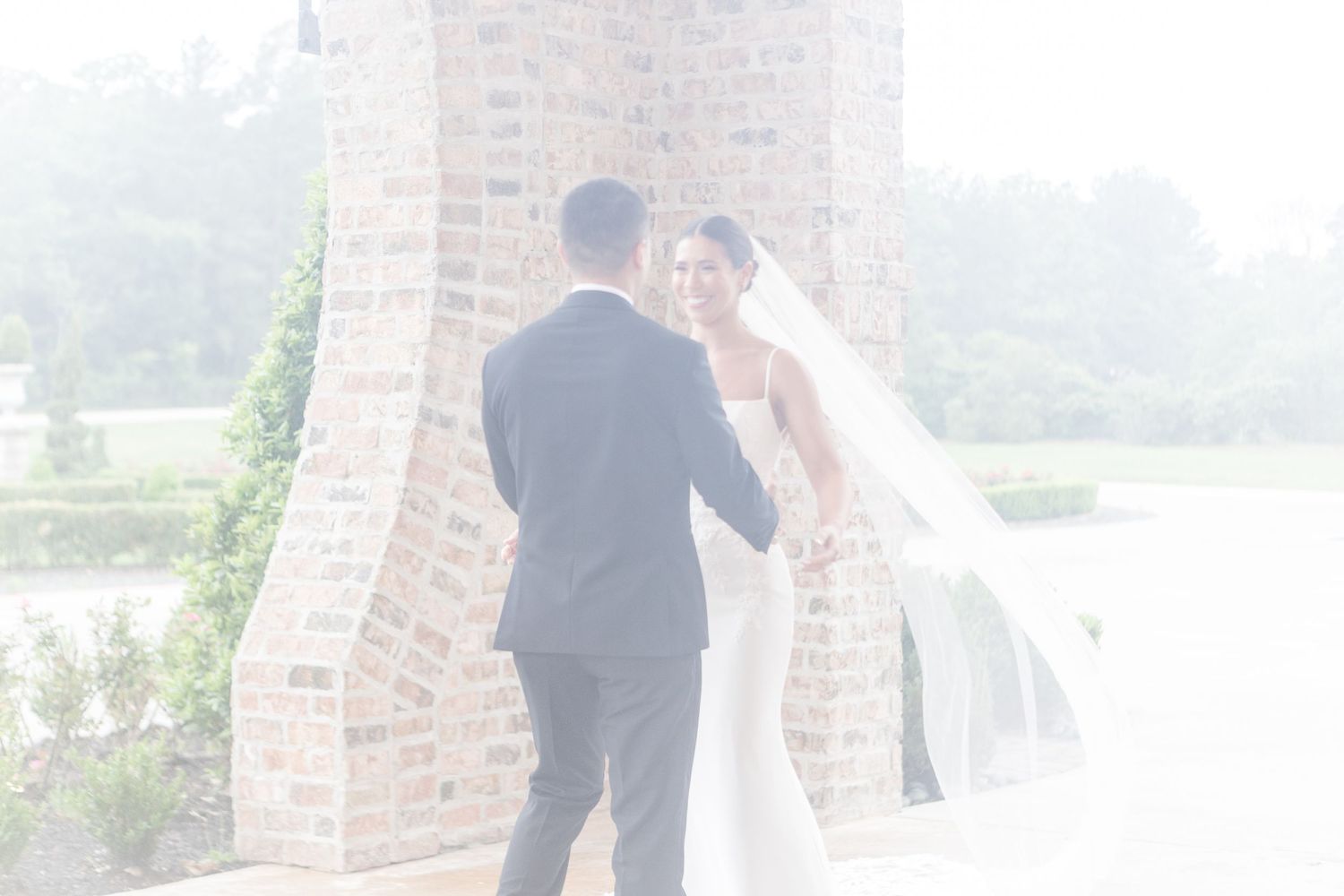 Romantic first look wedding moment captured on an outdoor brick terrace.