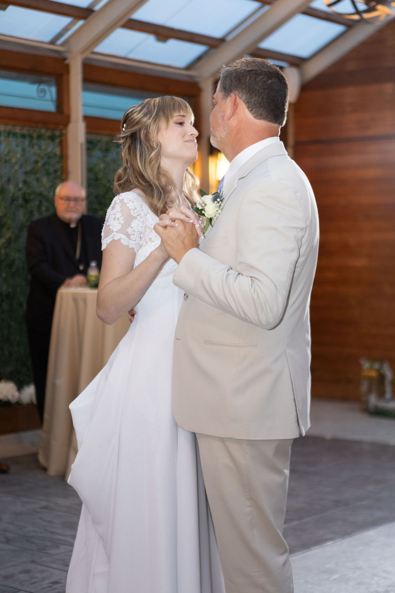 Elegant first dance in a wood-paneled reception space with natural light streaming through skylights.