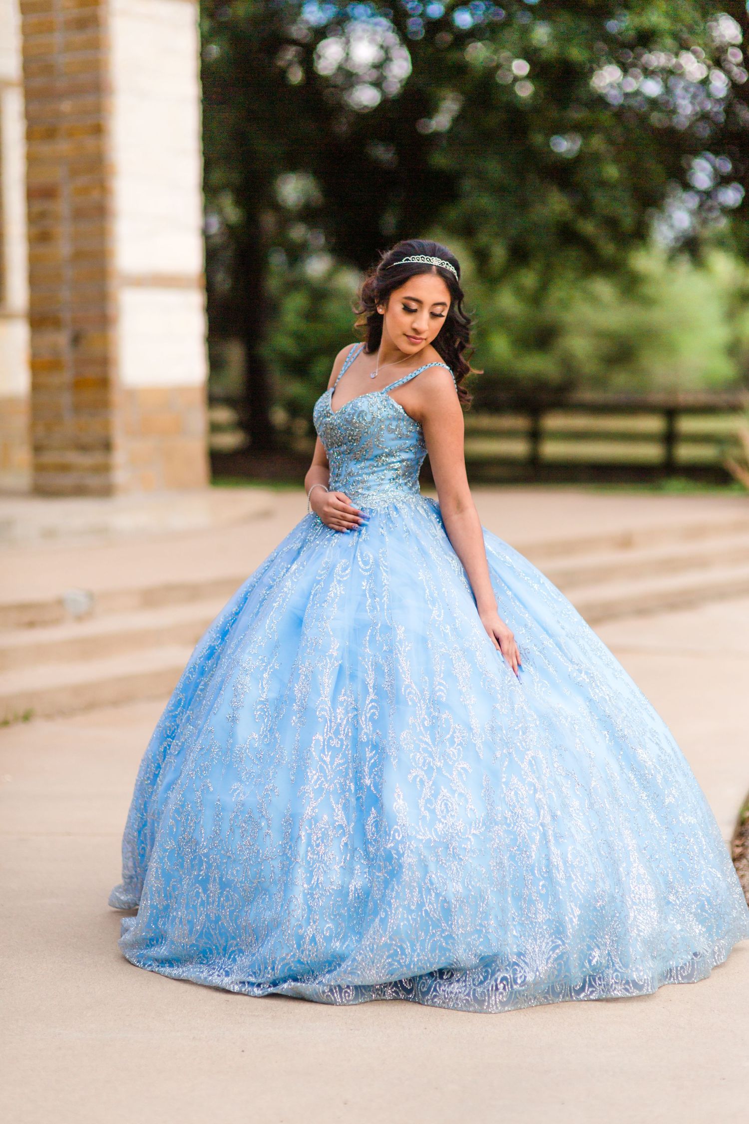Ornate light blue ballgown with sparkly details shown in various poses against brick architecture.