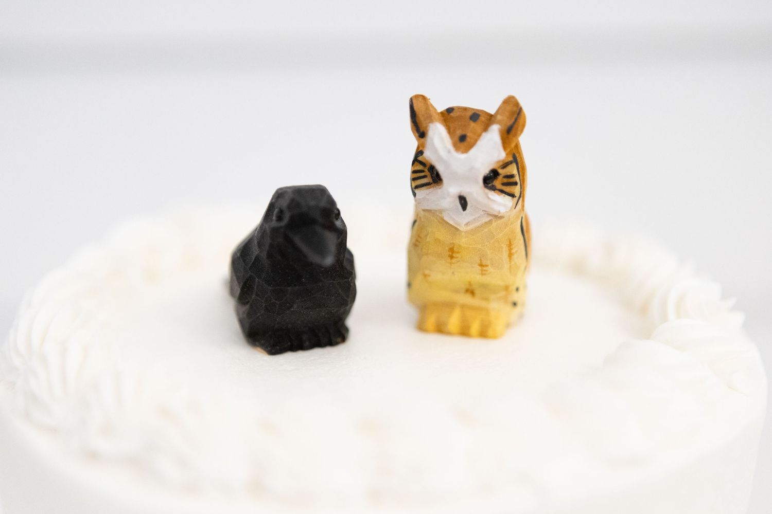 Decorative cat figurines placed on white textured surface.