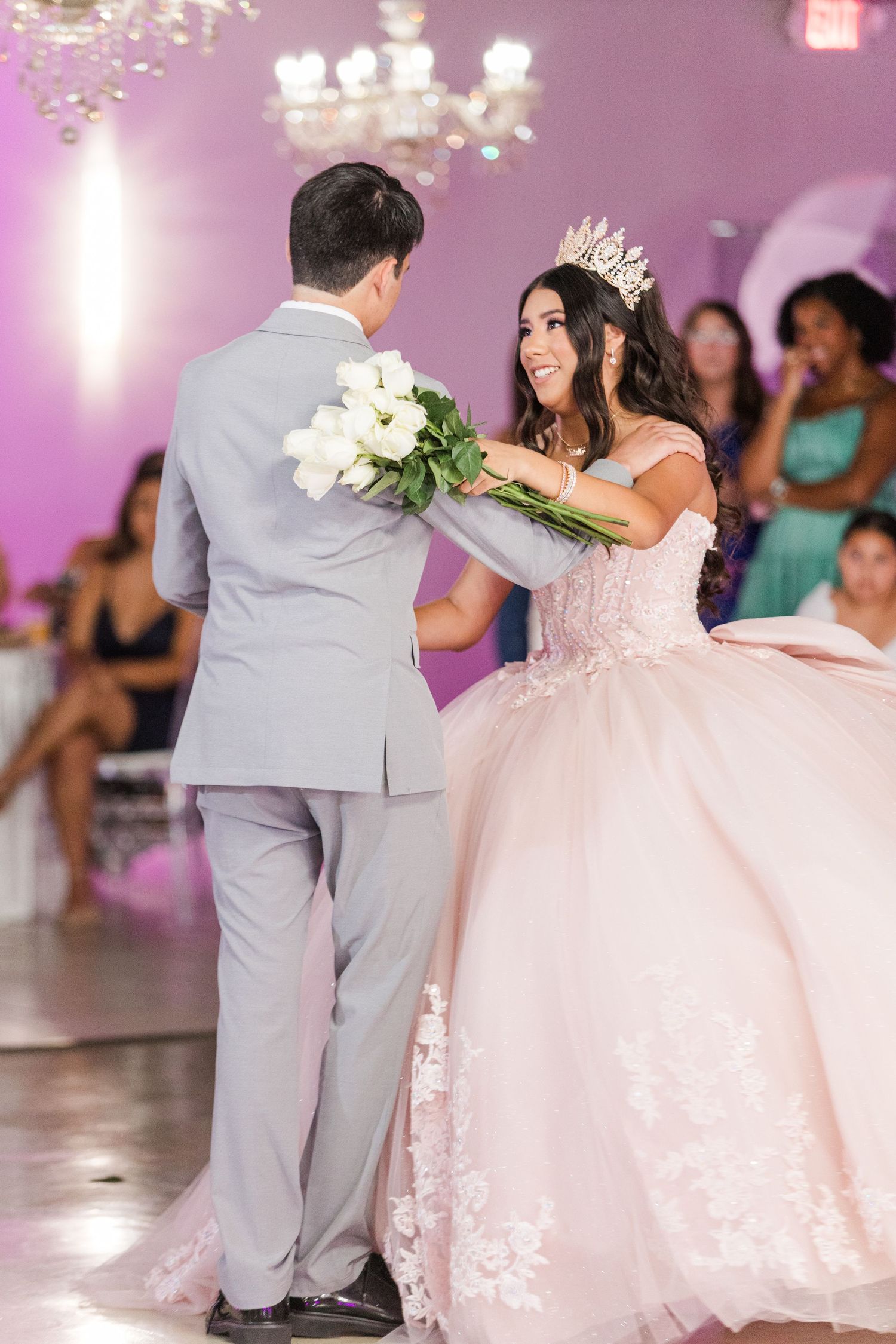 Sweet moment exchanging white flowers during a celebration in a beautifully lit purple venue.