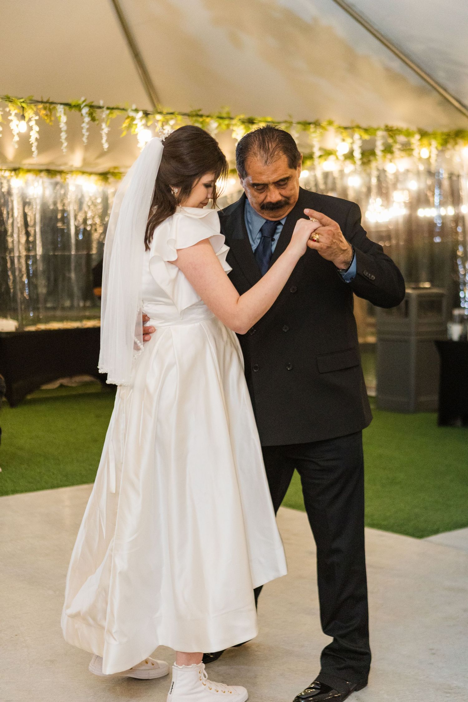 Wedding reception dance with couples on illuminated outdoor dance floor under tent.