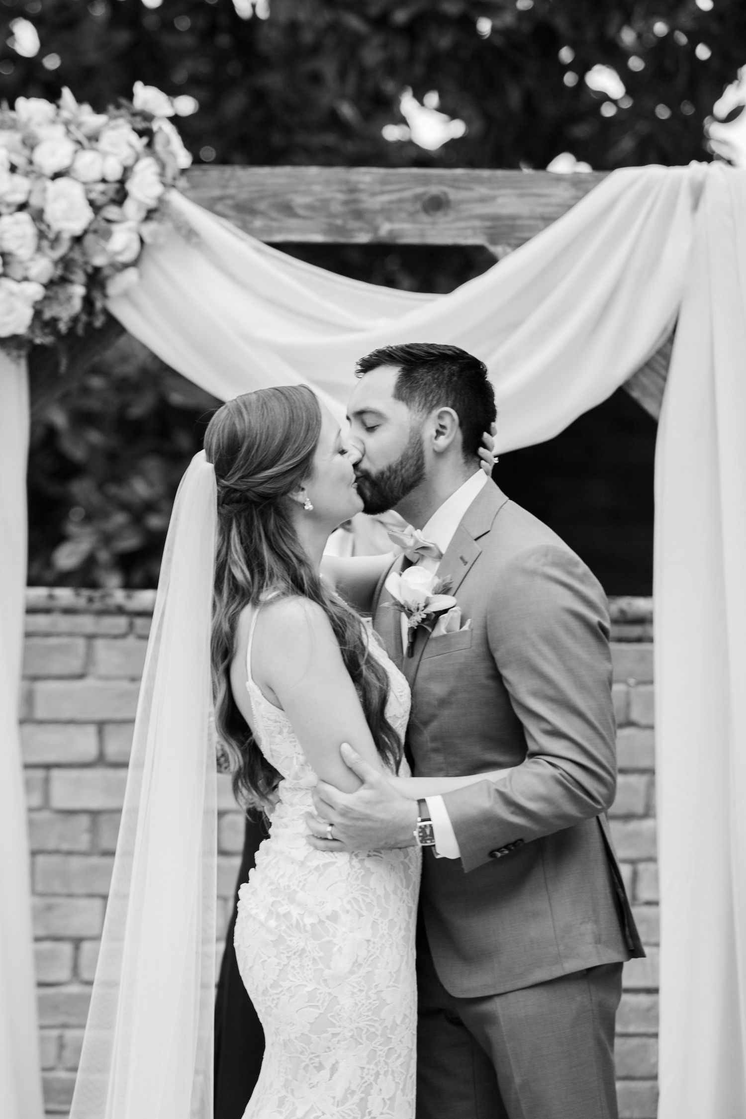 A romantic moment captured during an outdoor wedding ceremony under white drapery.