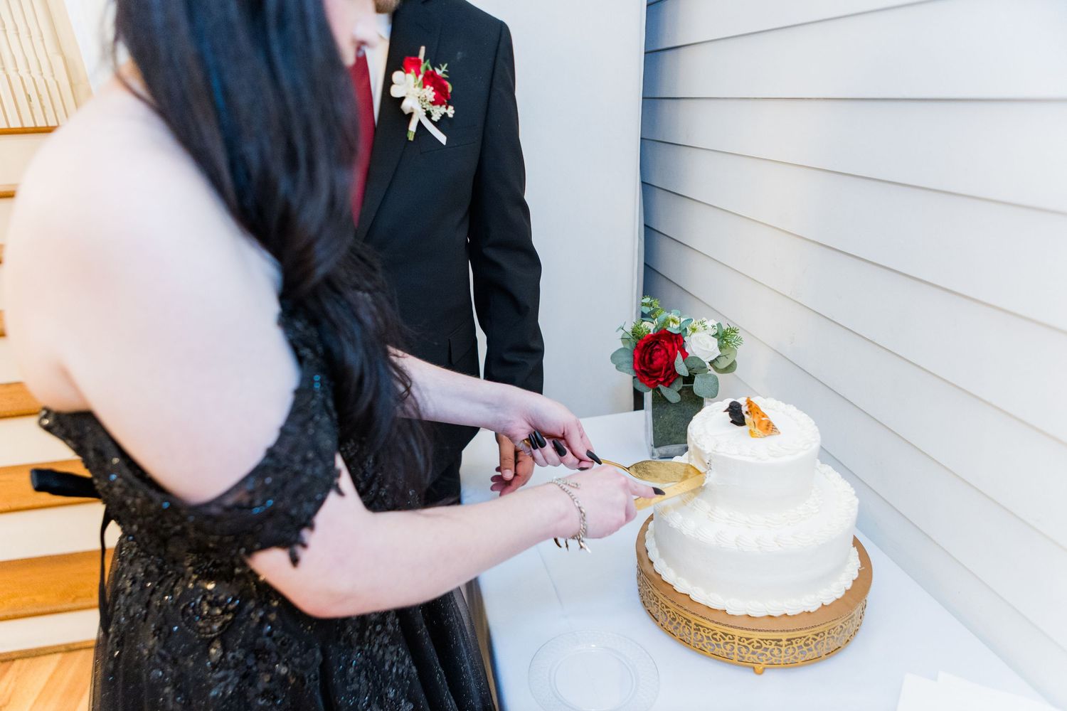 Wedding couple standing near white wall with cake display.