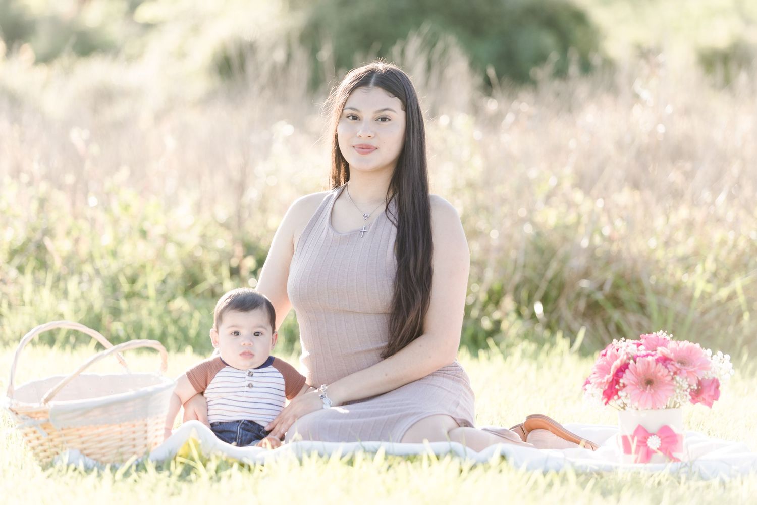 Dreamy outdoor maternity session with pink flowers and natural lighting.