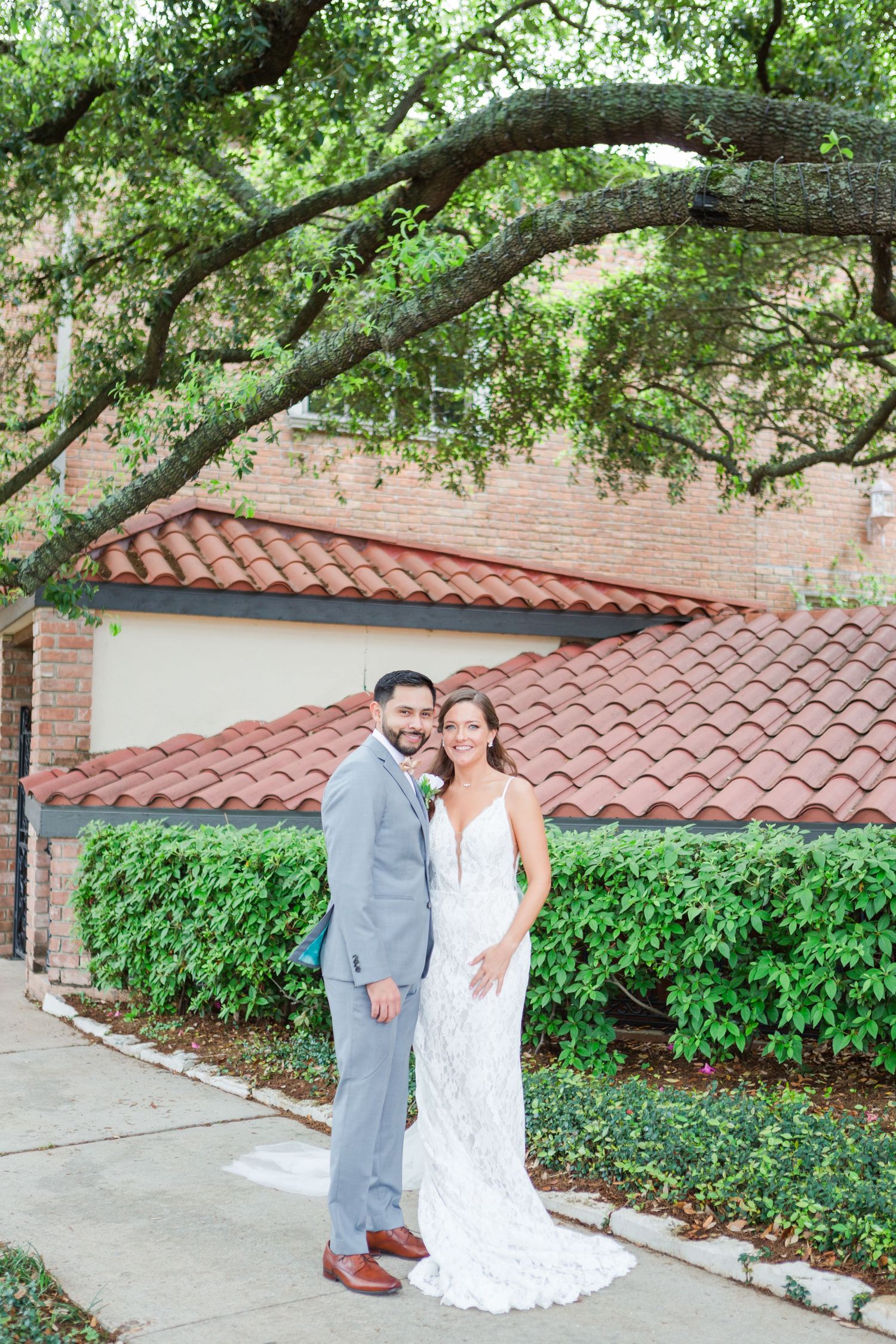 Wedding photography scene with Spanish architecture, terra cotta roof and overhanging trees.