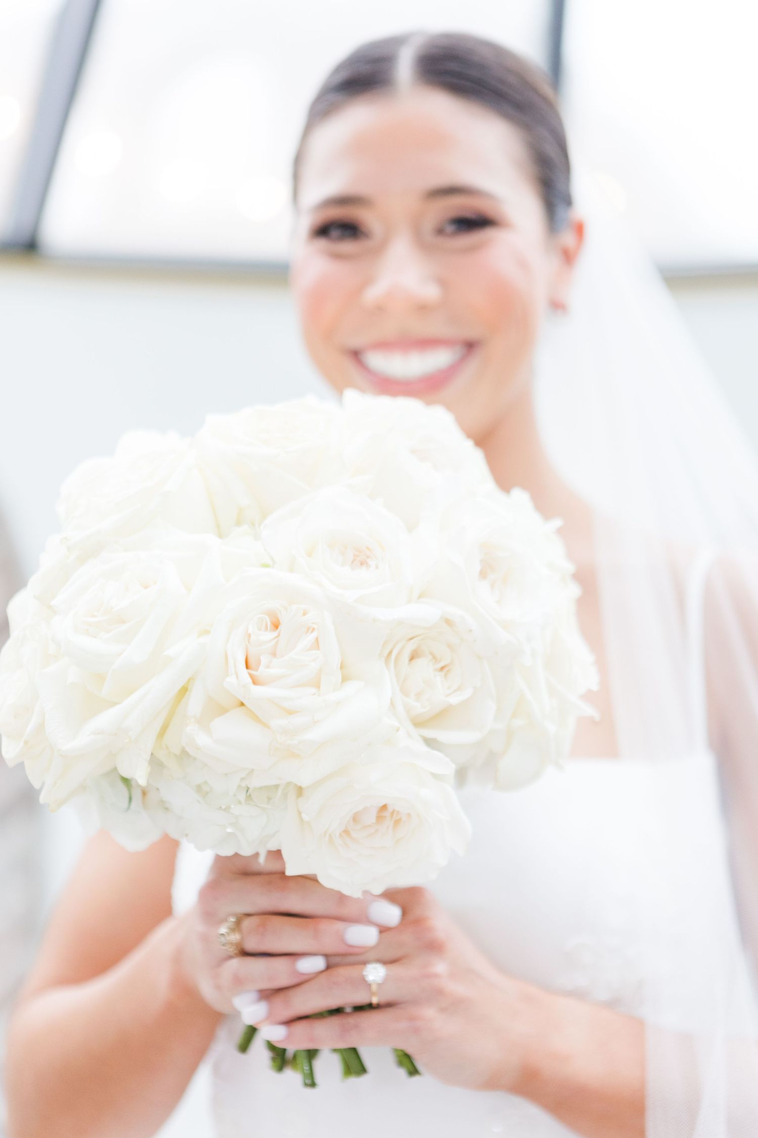 Close-up shots of a pristine white rose wedding bouquet held by hands with manicured nails.